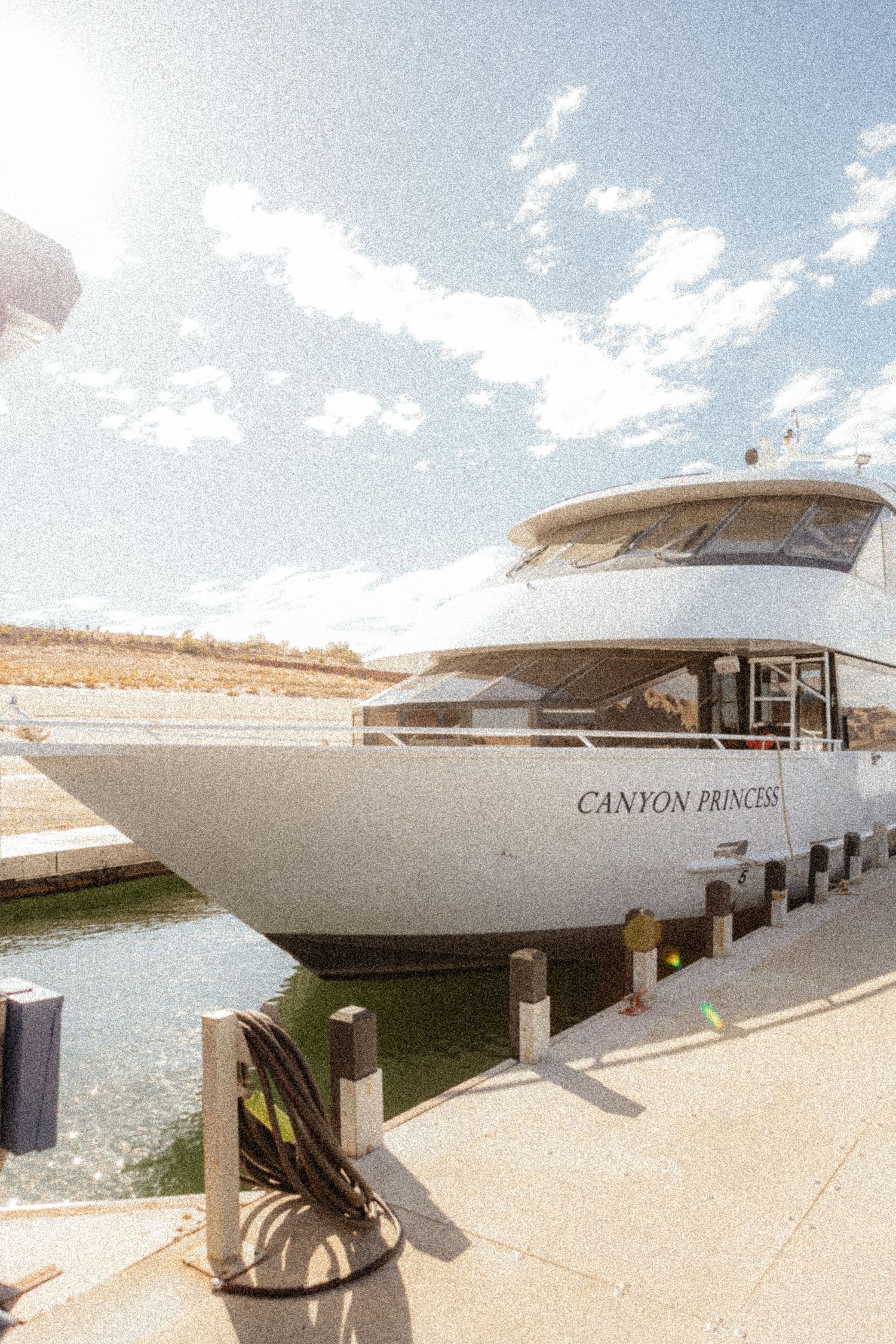 Luxury white yacht Canyon Princess docked at marina with bright blue sky and water in background.