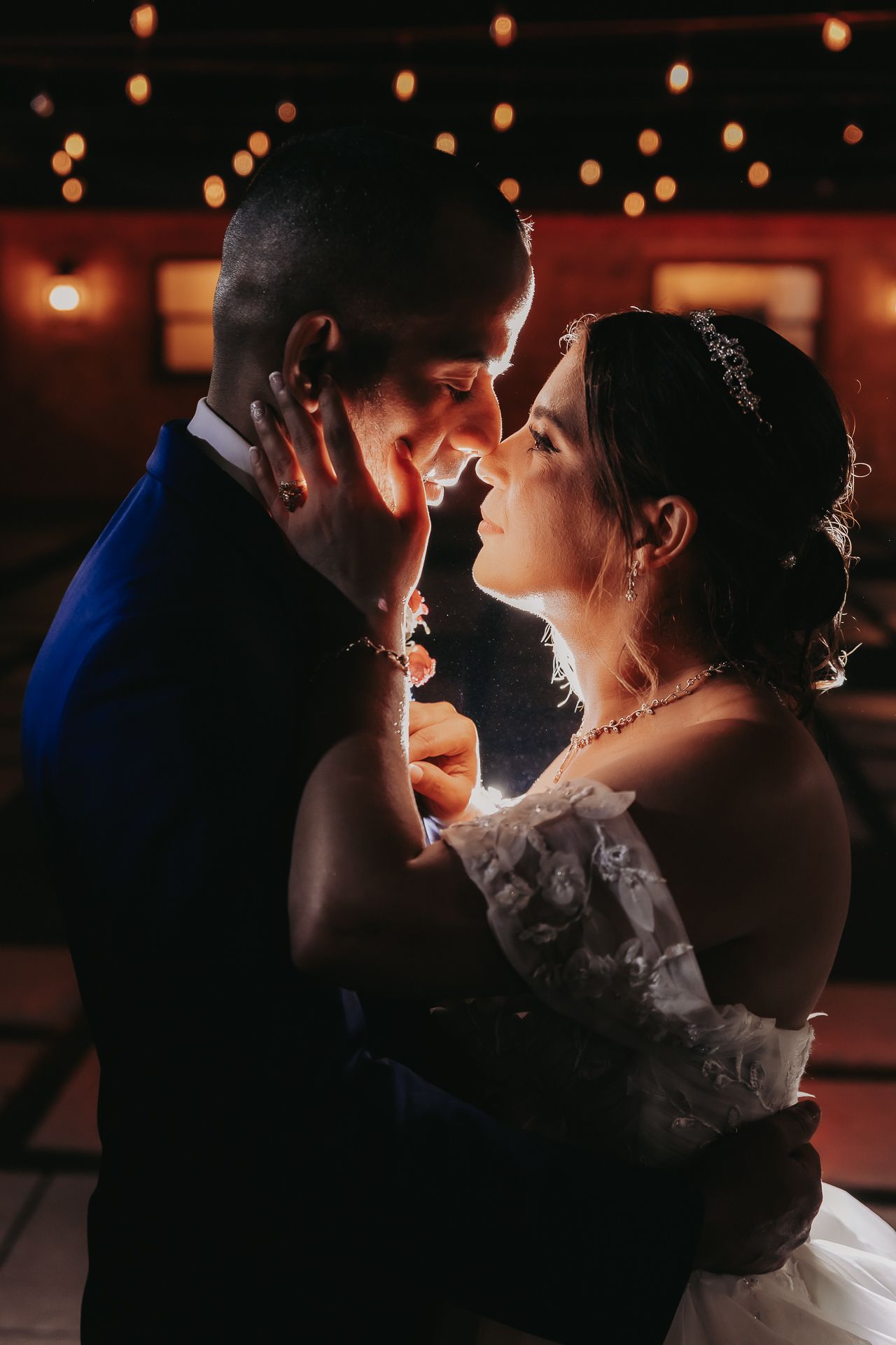 A romantic moment between newlyweds sharing their first dance under warm lighting at their wedding reception.