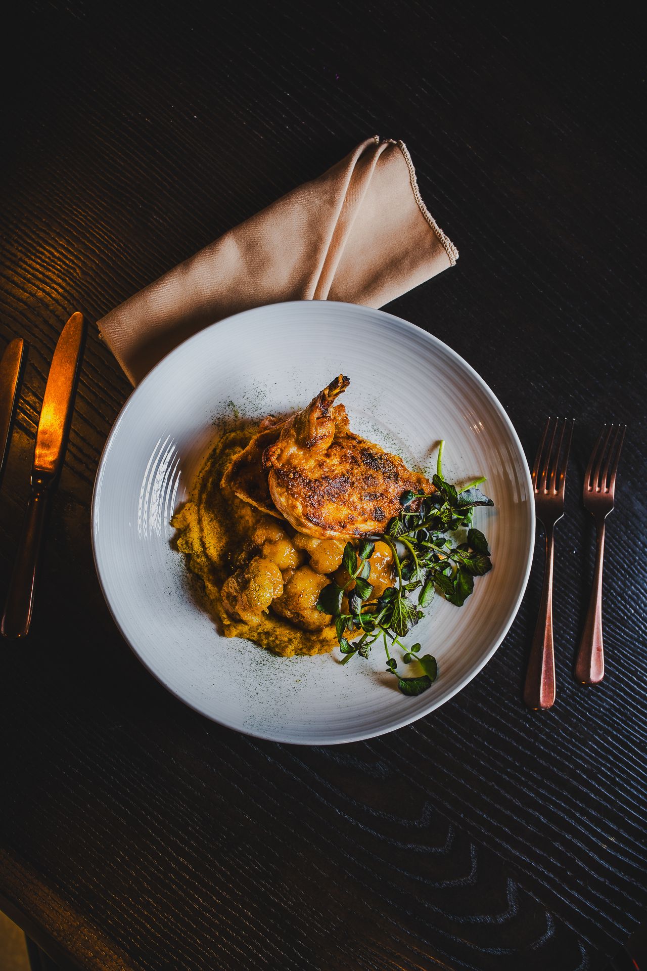 Roasted chicken dish with vegetables and greens plated elegantly on white ceramic dish.