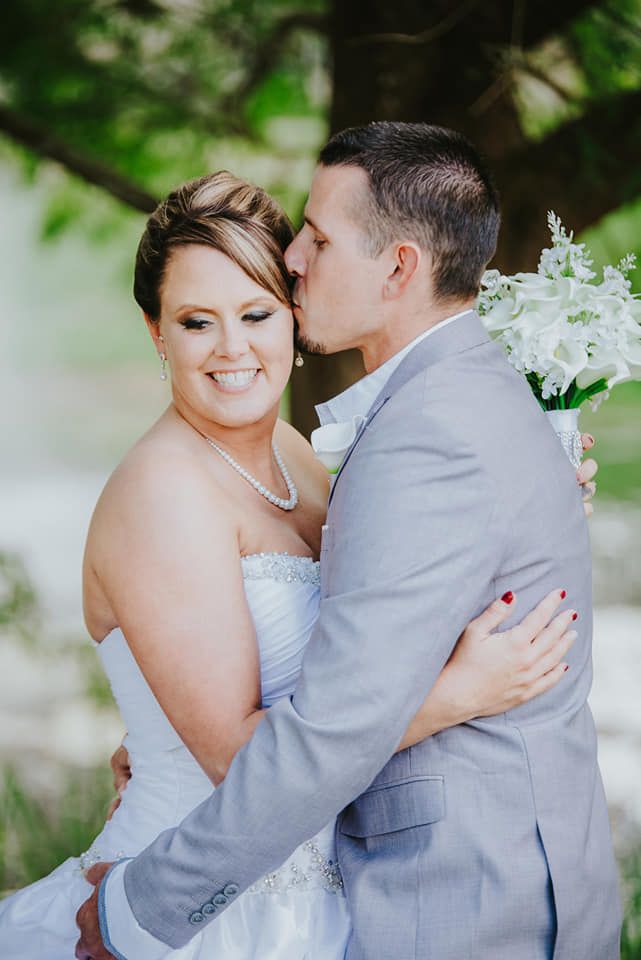 Romantic outdoor wedding portrait of a couple embracing in formal attire.