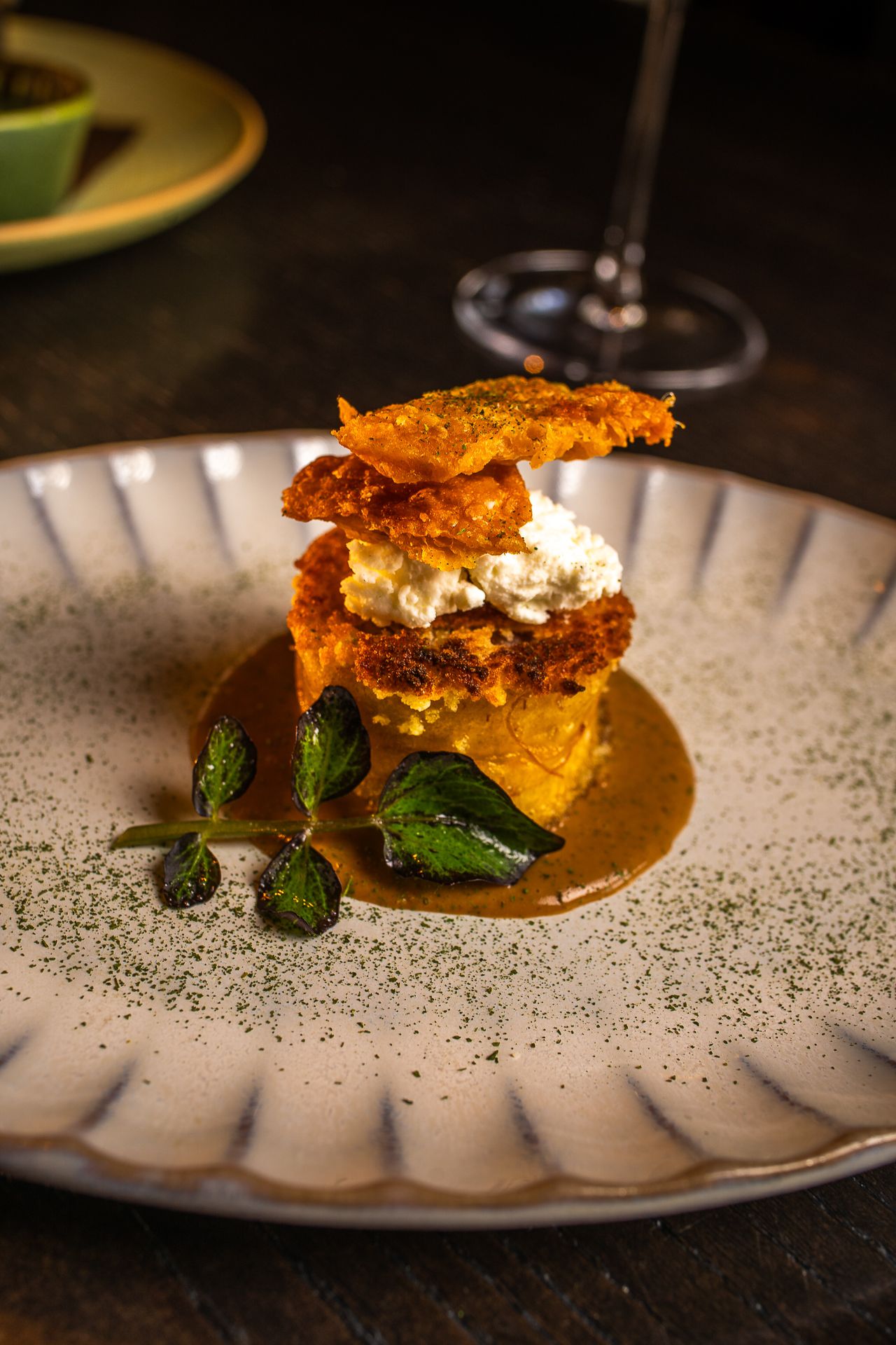 Gourmet stacked appetizer with crispy layers and creamy filling on decorative ceramic plate.