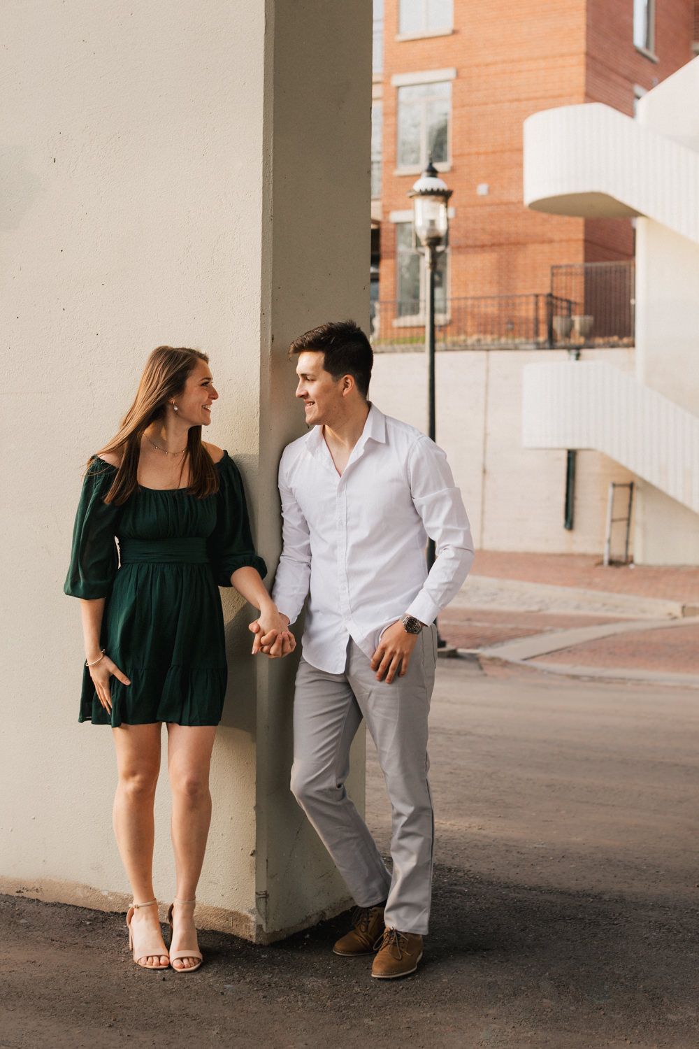 Couple in casual attire sharing laughs while sitting in an urban colonnade.