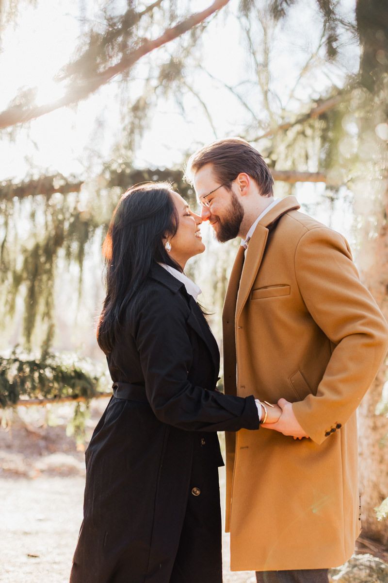 A loving couple embraces under Spanish moss wearing stylish winter coats.