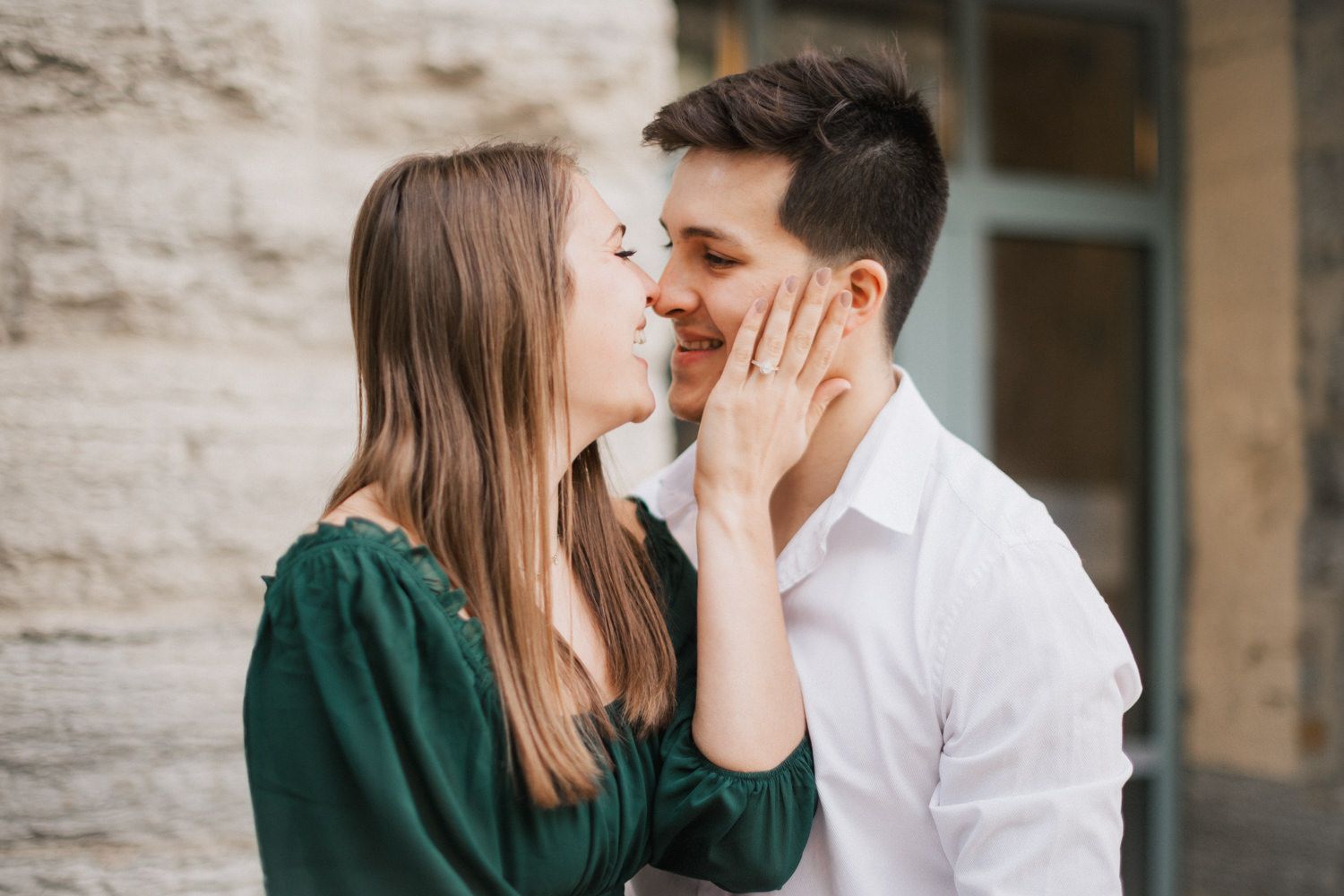 Intimate moment between couple against stone wall backdrop.