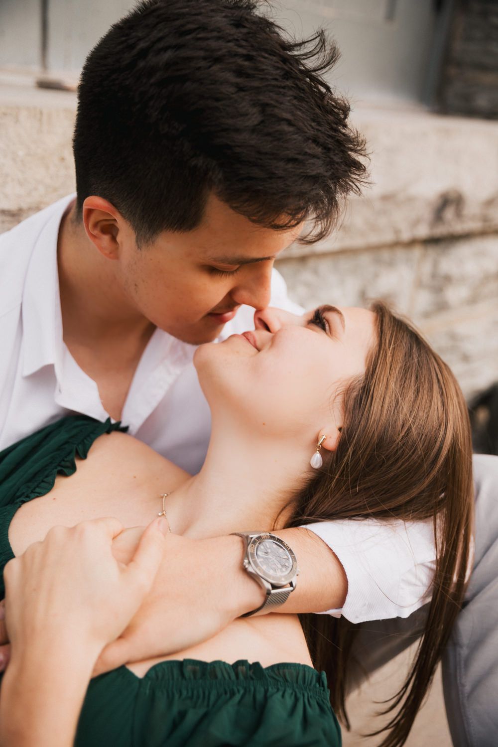 A romantic couple sharing an intimate moment, with the woman wearing a green dress and silver watch.