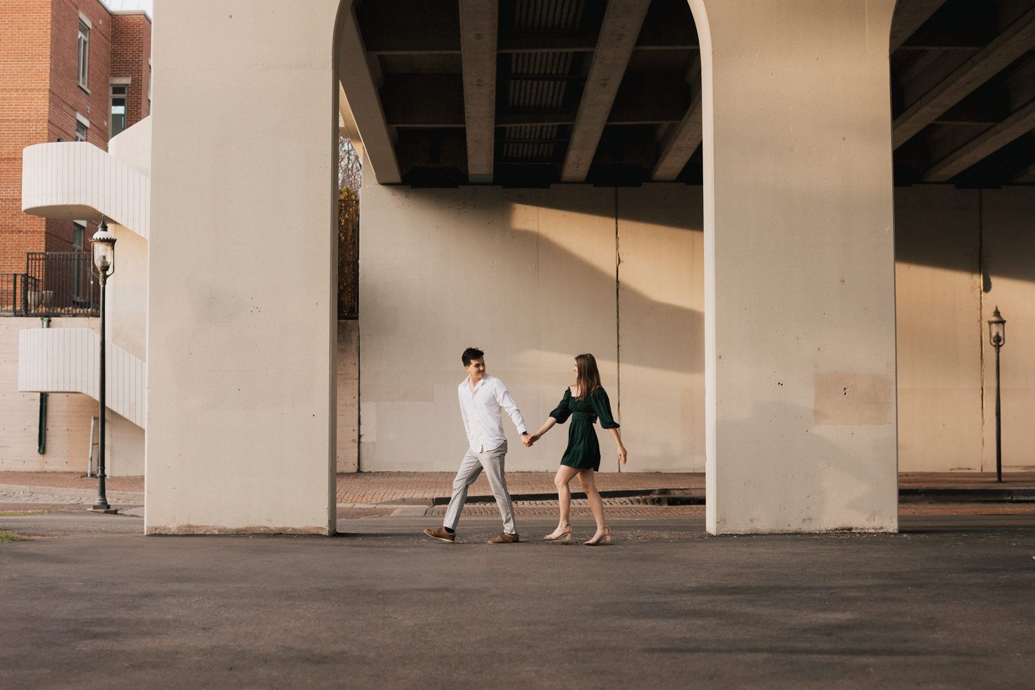 Wide architectural shot of a couple walking through a covered urban walkway.