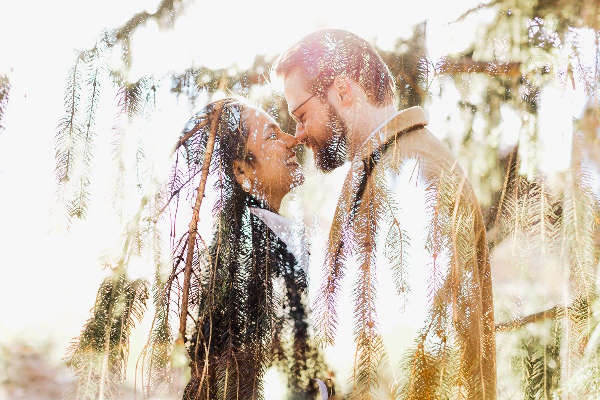 Dreamy double exposure of couple sharing tender moment under willow branches.