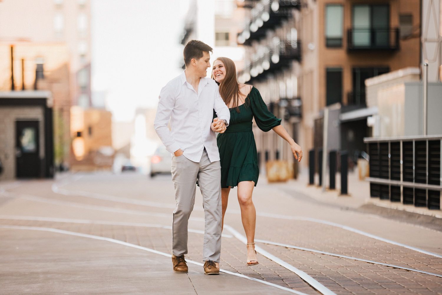 Couple walking together on city street during golden hour.