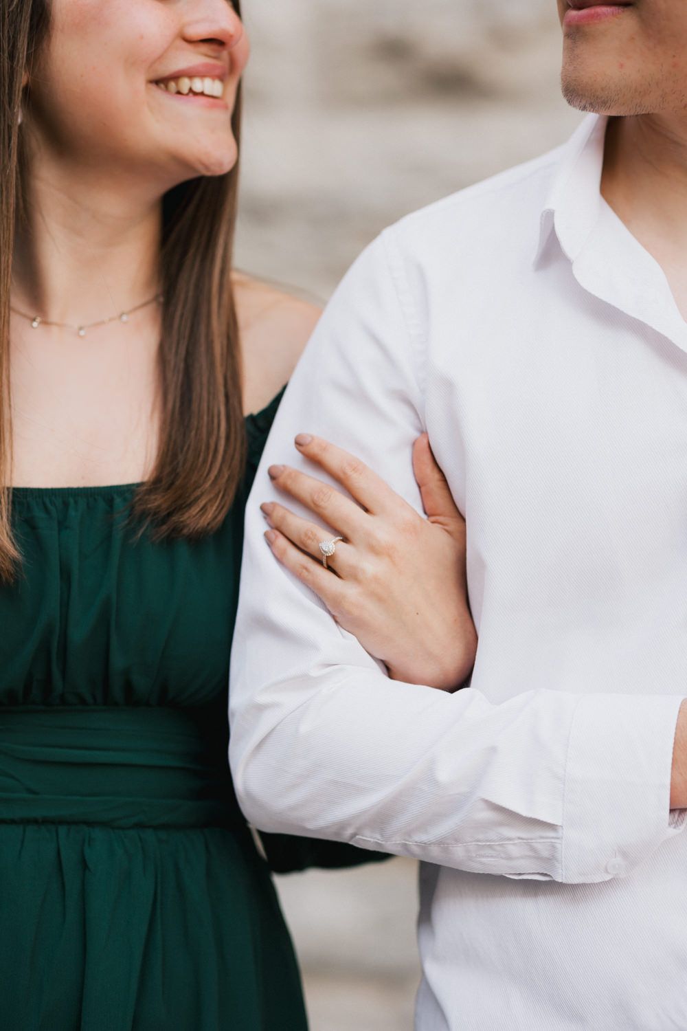 Intimate portrait showing engagement ring and couple's clothing details.