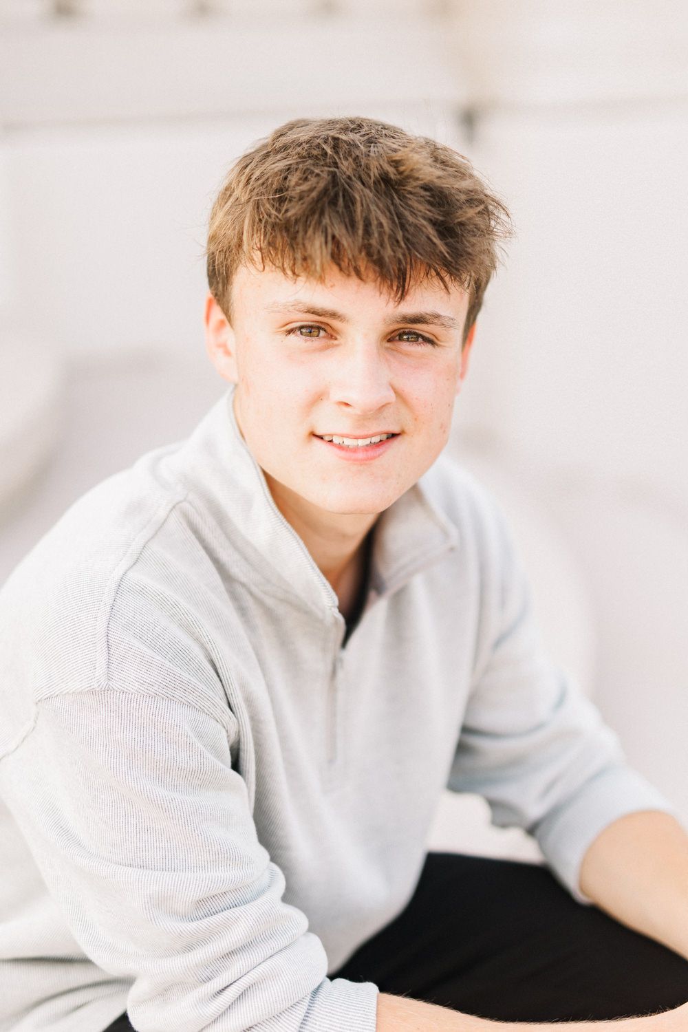 Portrait of someone in gray sweatshirt against light colored wall background.