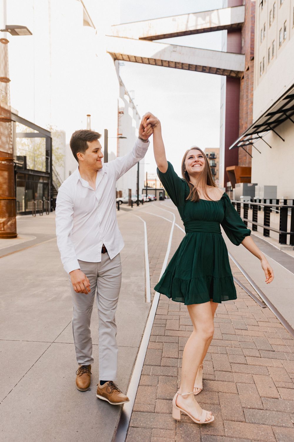 Couple dancing and twirling on urban walkway.
