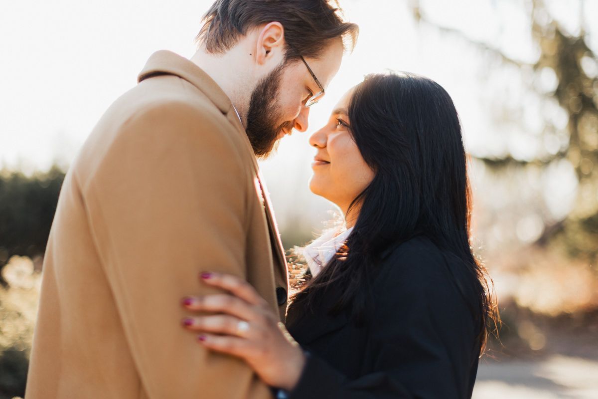 A romantic couple shares an intimate moment outdoors during golden hour sunset.