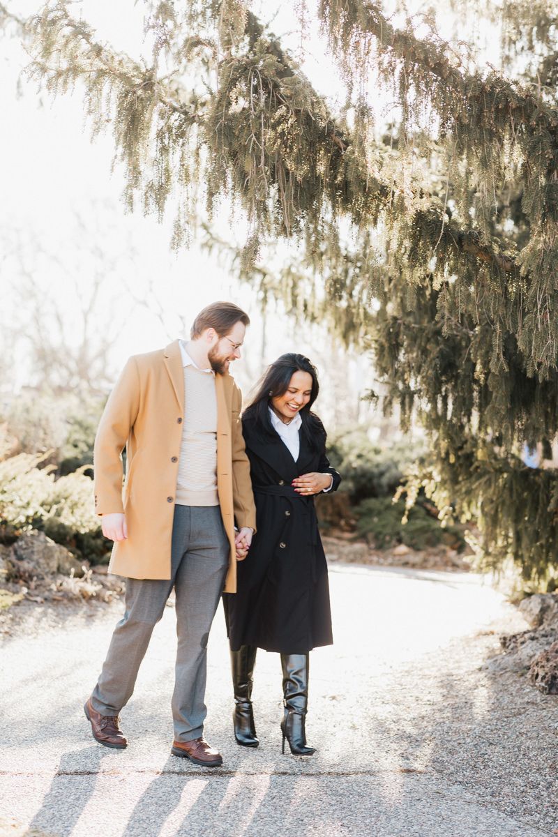 A couple in stylish coats walking together on a winter path.