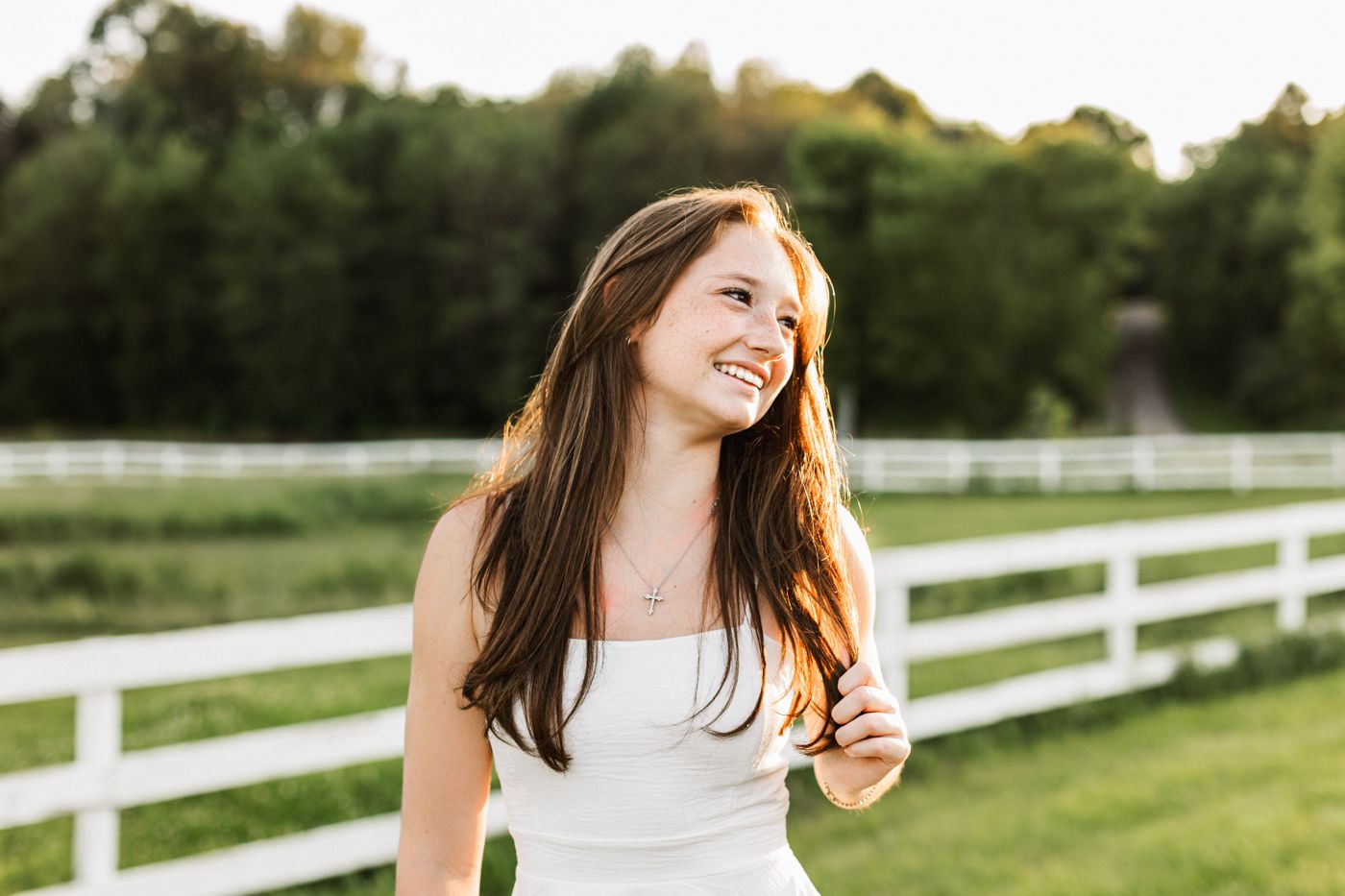 A joyful outdoor portrait against white fence and green pasture background.