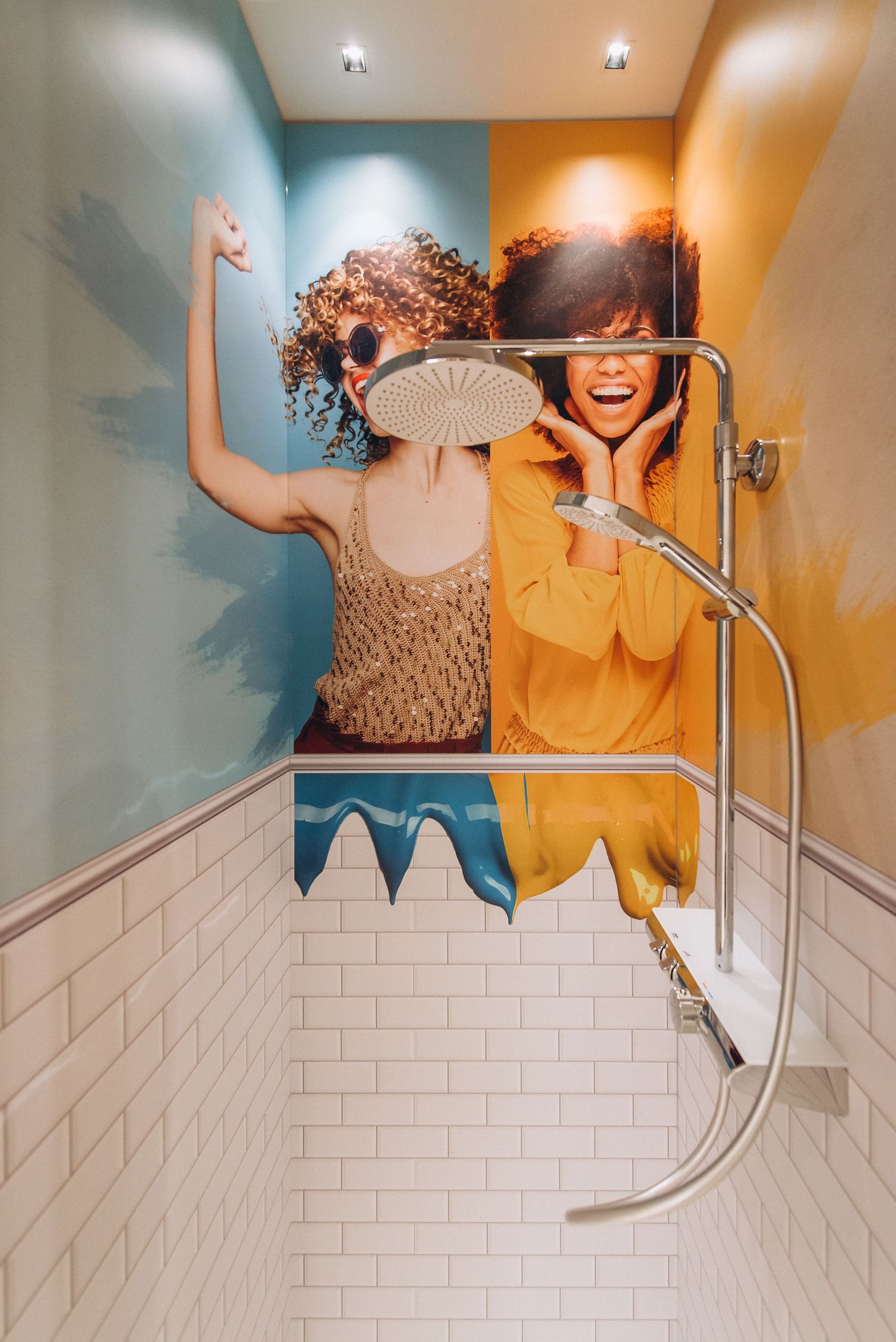 Bathroom wall with playful colorblock paint design in orange and blue tones above white subway tile.