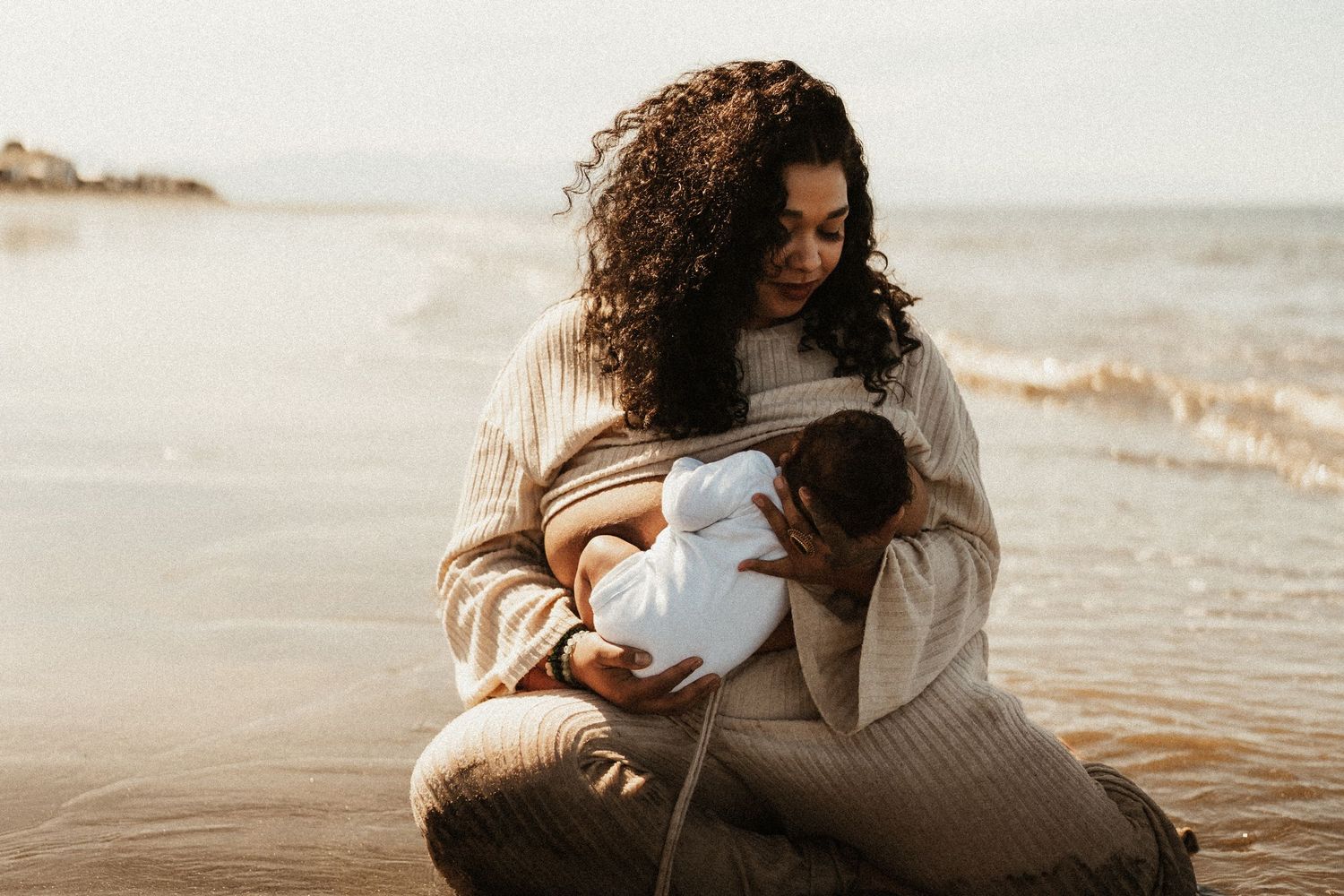 Cozy beach photography session with soft neutral tones and ocean waves in background.