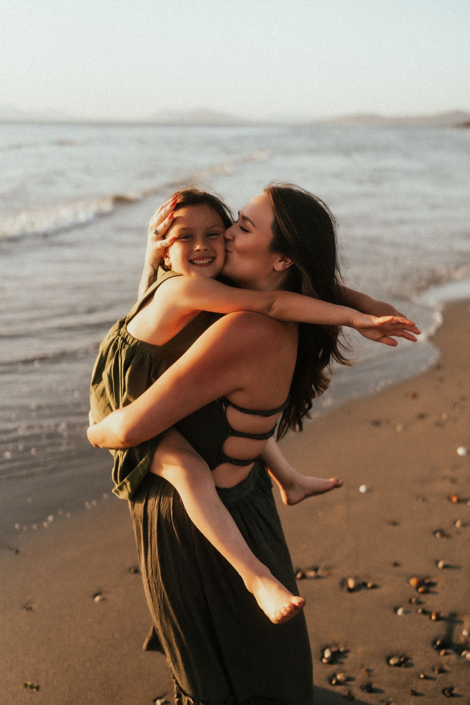 Joyful dance movements on a sandy beach at sunset with flowing dresses in earth tones.