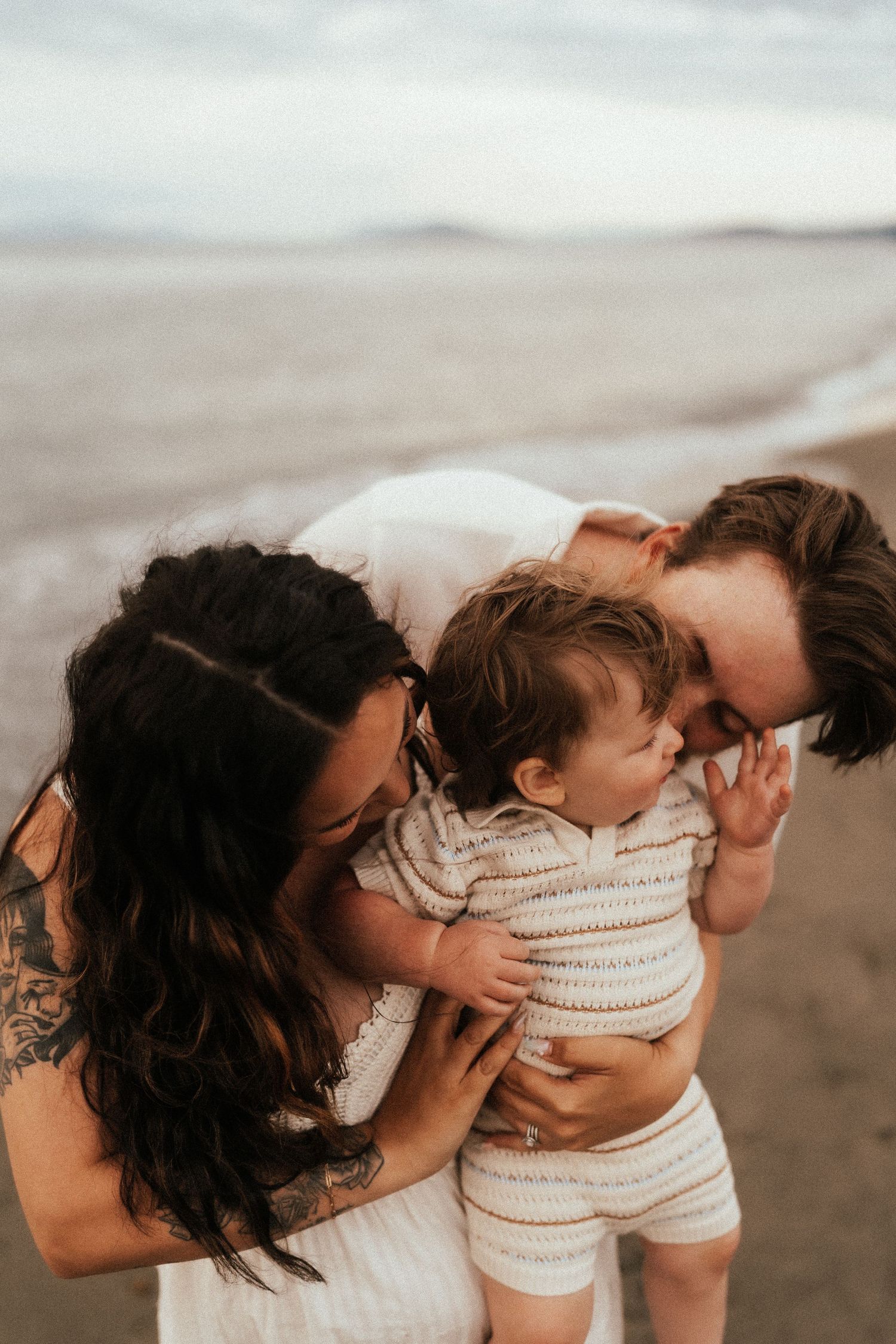 Intimate beach photoshoot showing tender moments by the ocean shore.