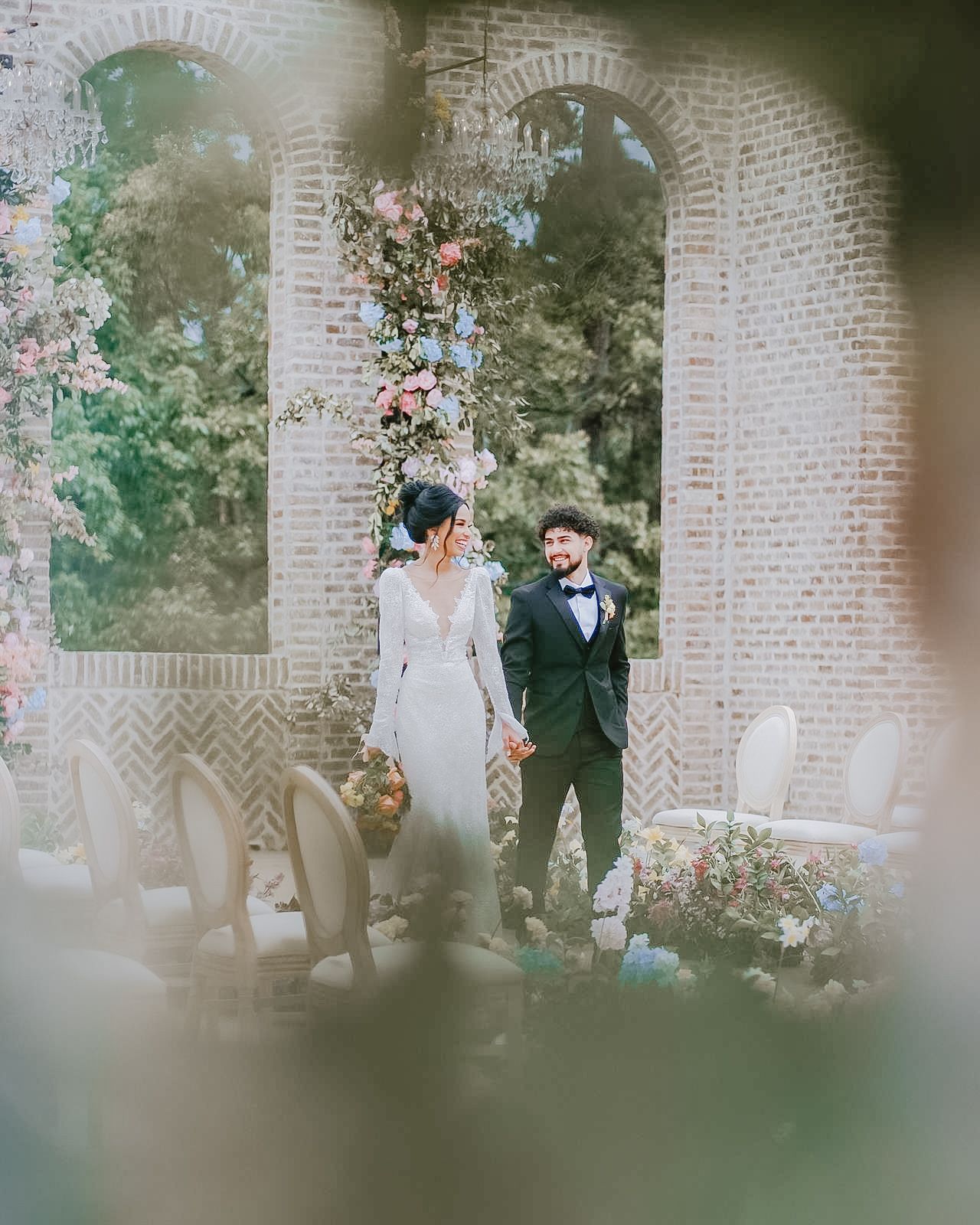 Elegant portrait of a mixed-race couple during a golden hour moment at a luxury outdoor reception venue in Huntsville, AL — surrounded by fl