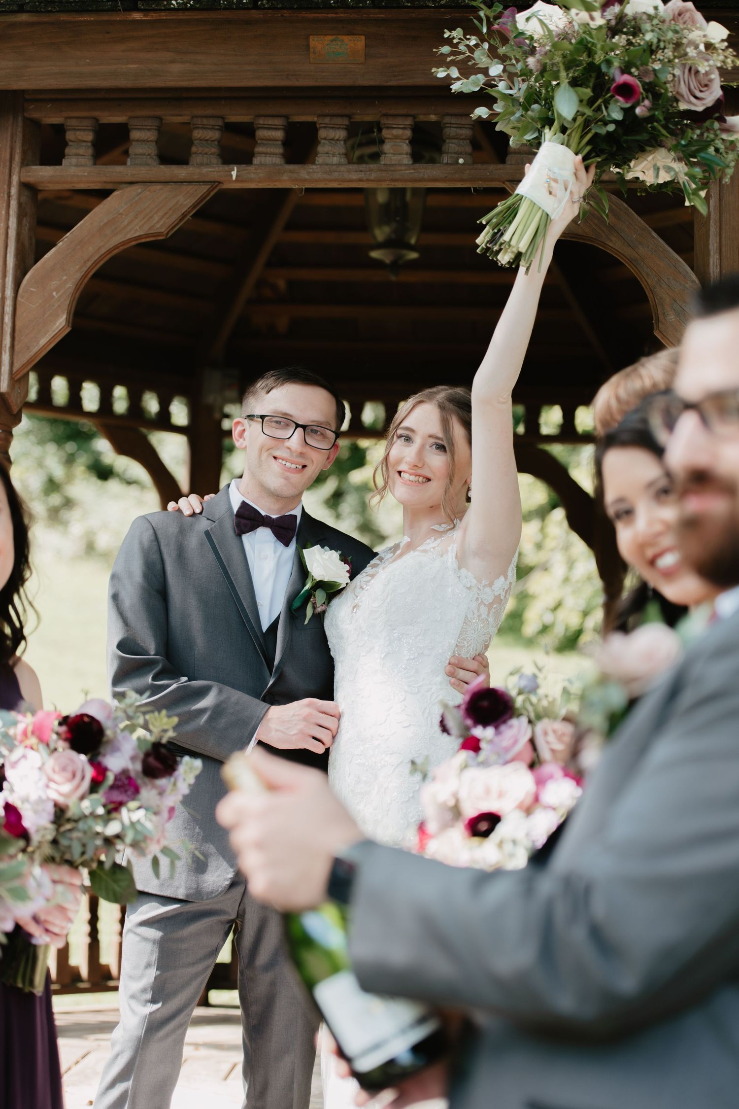 Candid moment of a joyful bride raising her bouquet in celebration just after saying ‘I do’ — captured in a documentary-style frame with sof