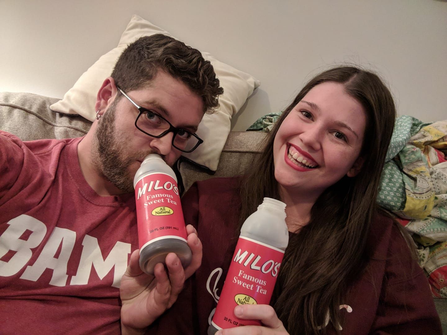Couple in casual setting drinking Milos Tea on a couch with cheery smiles