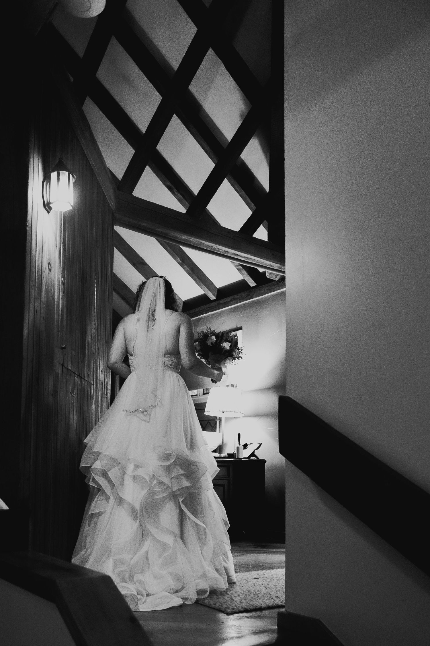 Timeless black and white portrait of a bride gracefully walking up elegant stairs, captured with an artistic, documentary style that highlig