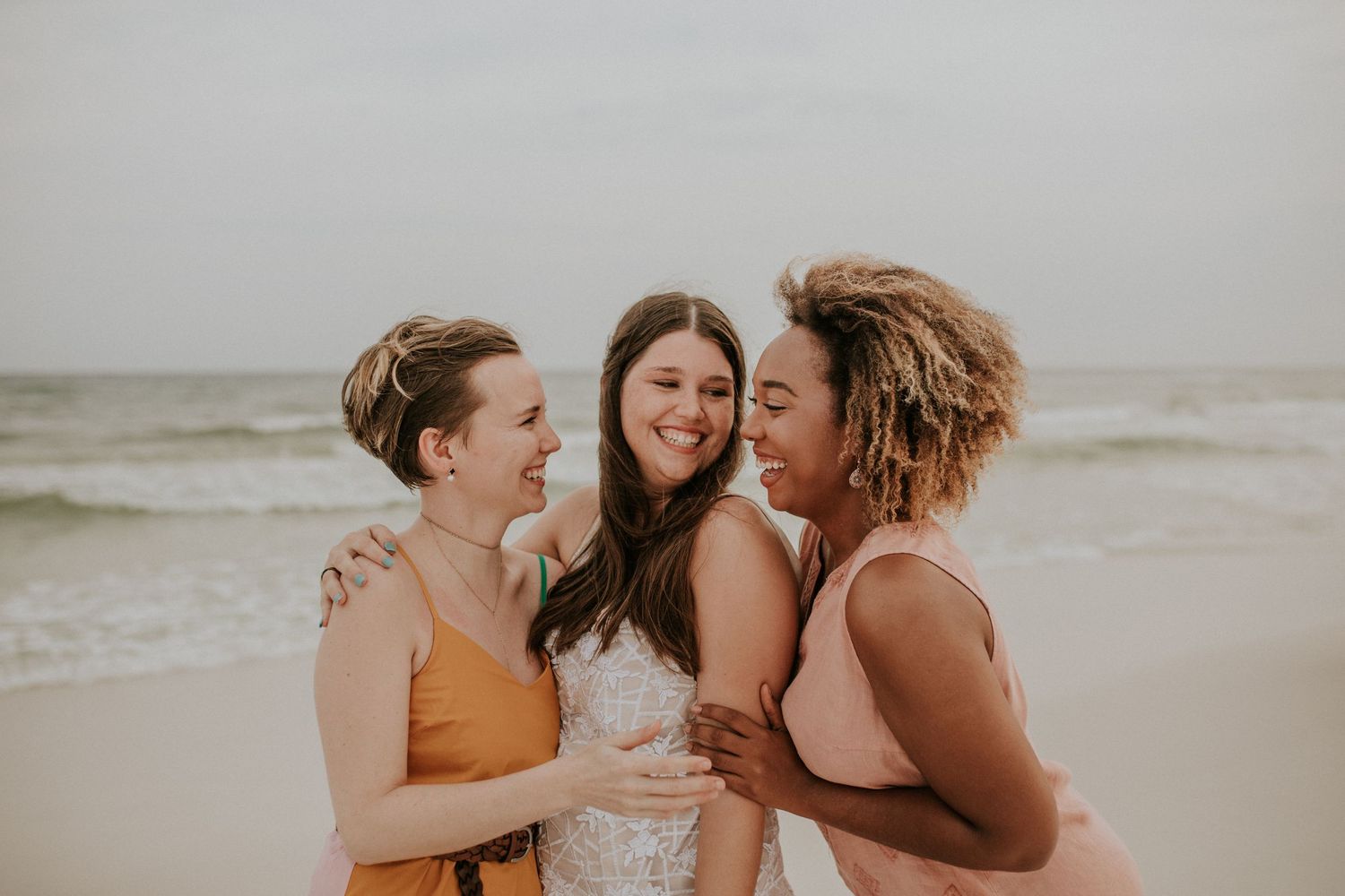 Destination beach ceremony with neutral florals, captured in soft film tones with a modern edge
