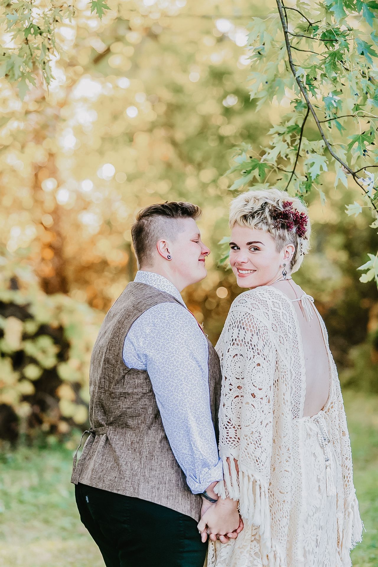 Dreamy portrait of a bohemian lesbian couple embracing in golden hour light at an outdoor wedding in Lehigh Valley, PA — adorned in flowing