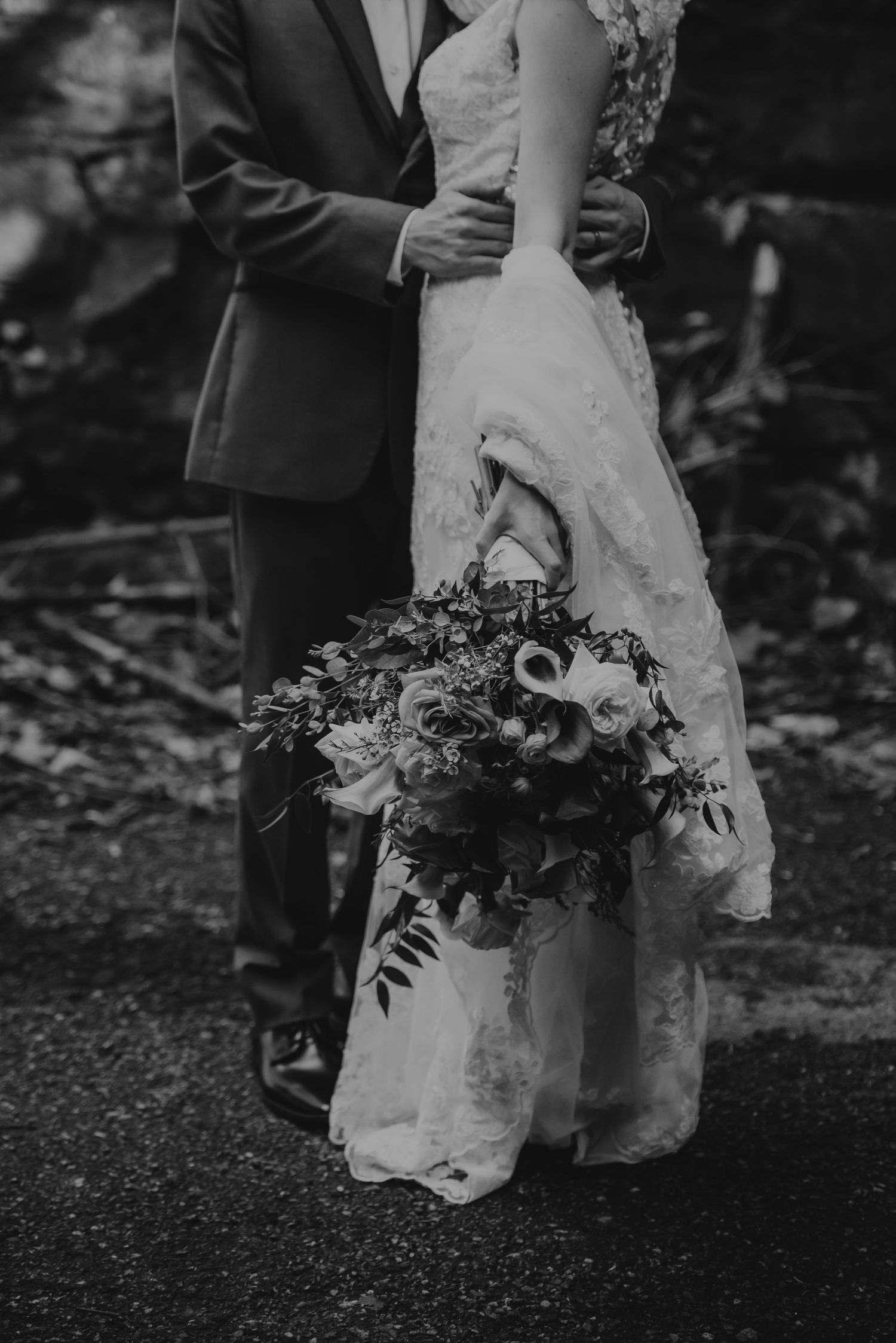 Editorial Black and White Film Photograph of a wedding couple holding each other. Close up on dress and bouquet in Philipsburg, NJ