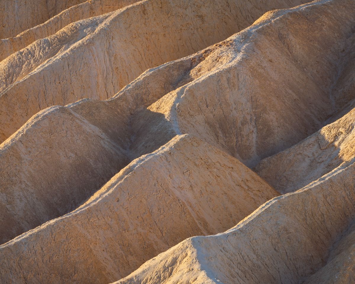 Desert badlands carved with diagonal erosion patterns in golden afternoon light.