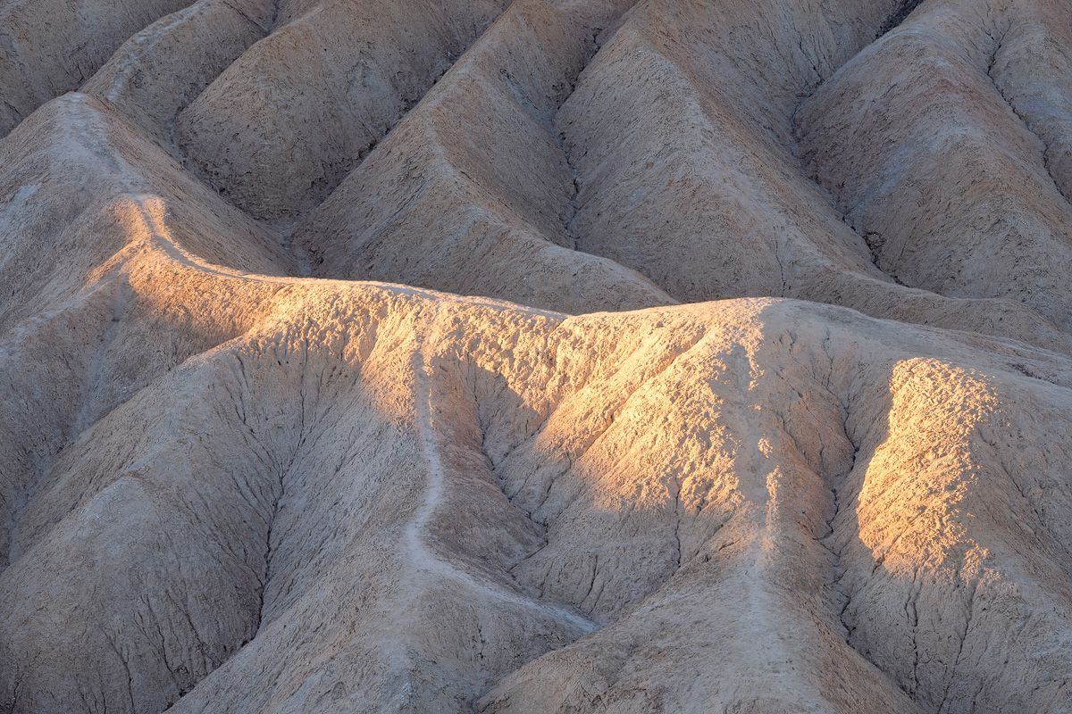 Eroded badlands terrain catching dramatic morning light and shadows.