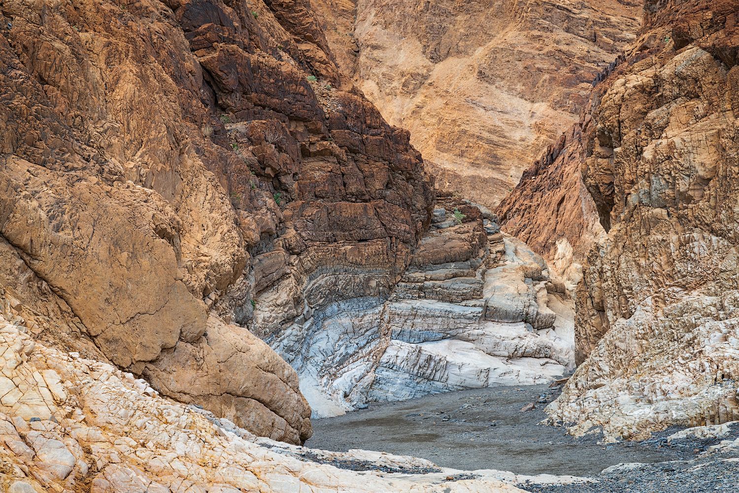Natural rock formations create a dramatic canyon corridor with textured walls in Death Valley.