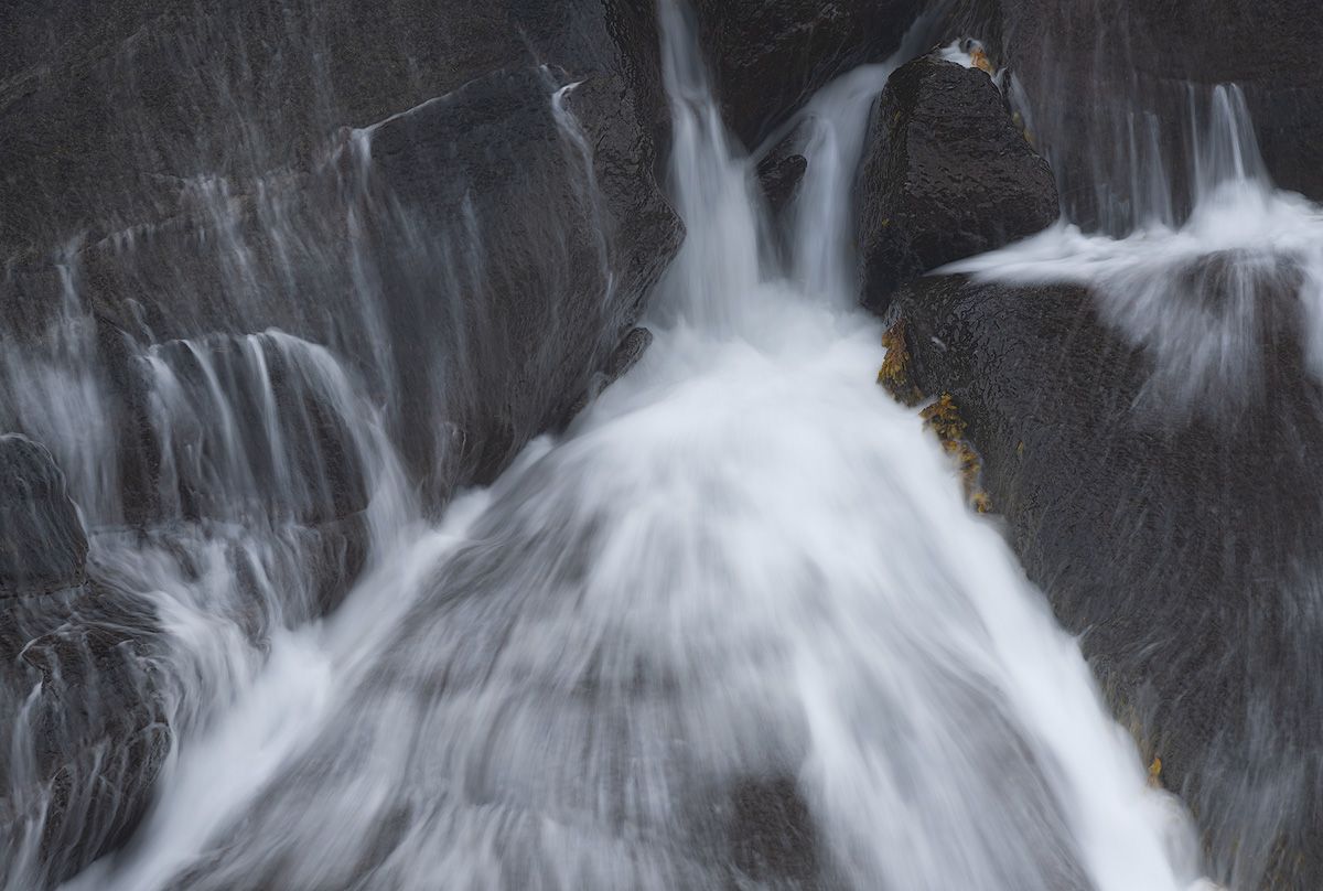 Cascading white waterfall flowing over dark rock.
