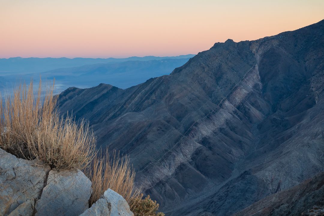 Mountain range silhouetted against a pink and blue sky during sunset.