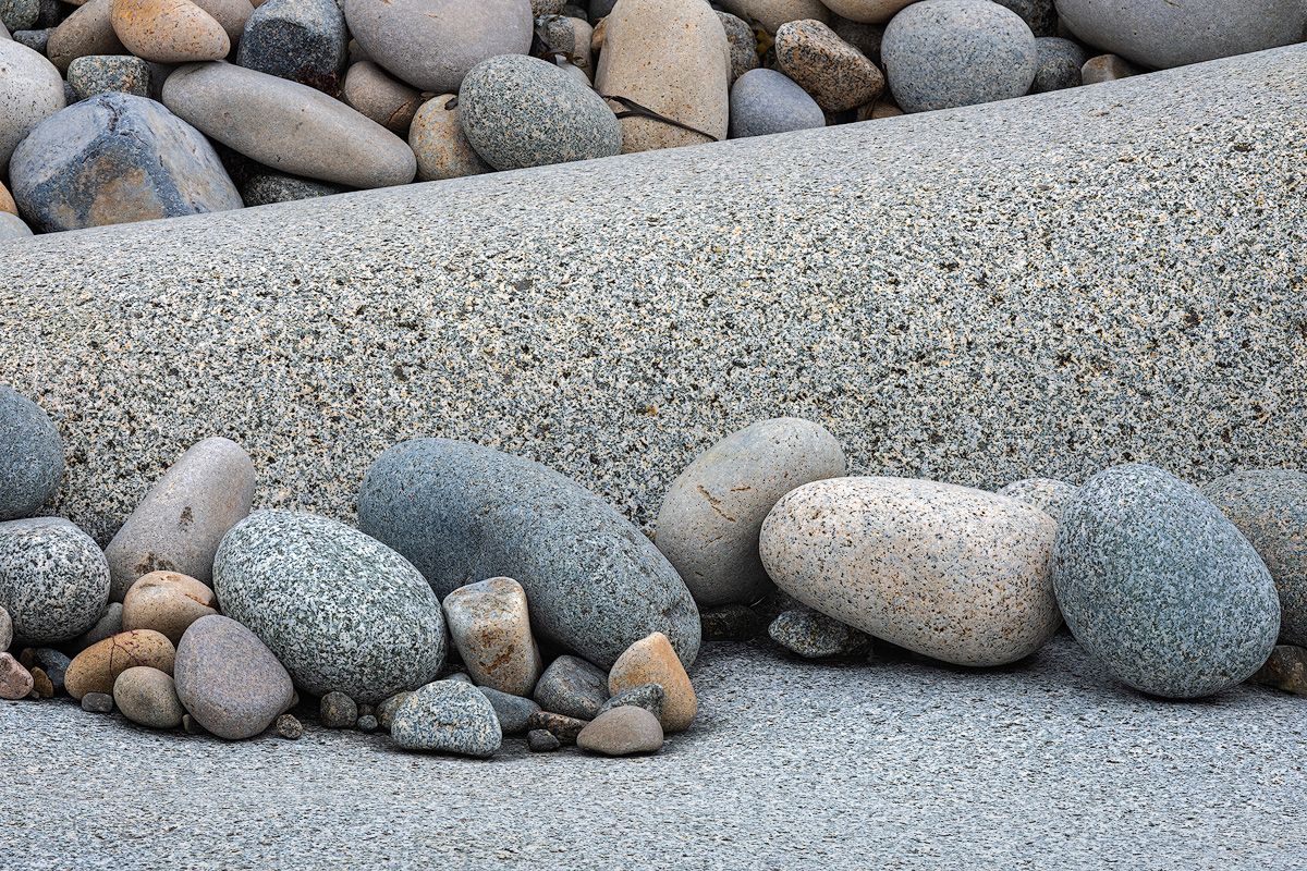 Smooth rocks and pebbles of various sizes and colors line a beach in Maine.