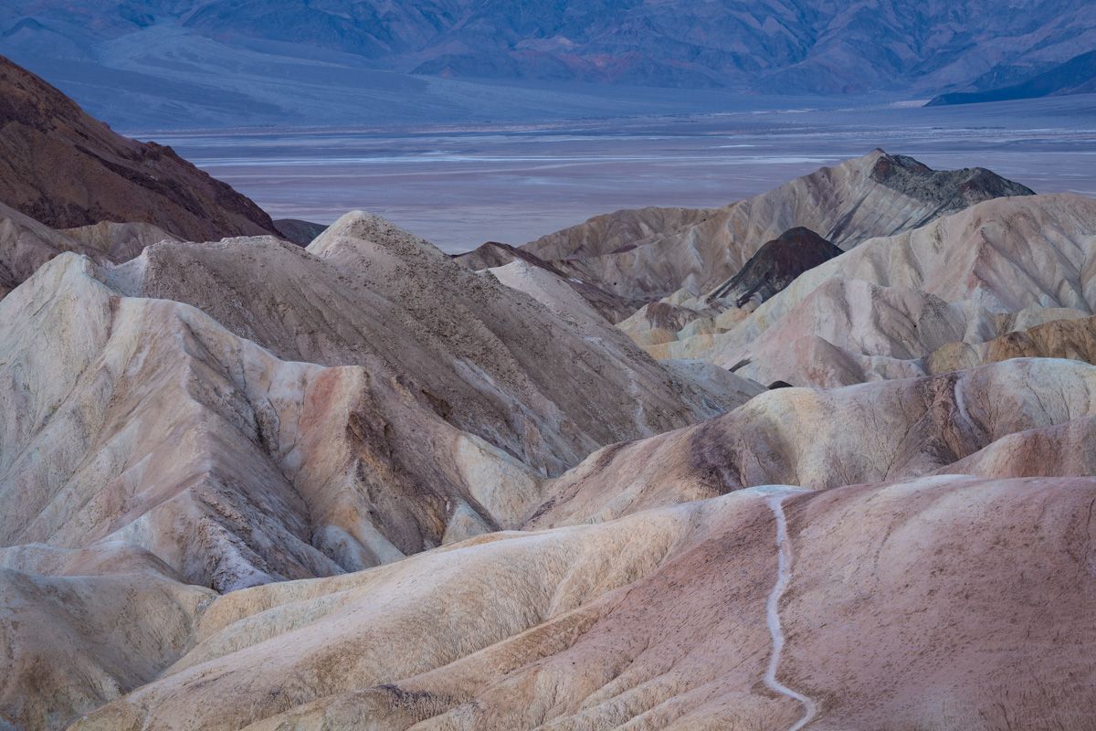 Colorful eroded badlands with layered rock formations stretching across a desert landscape.