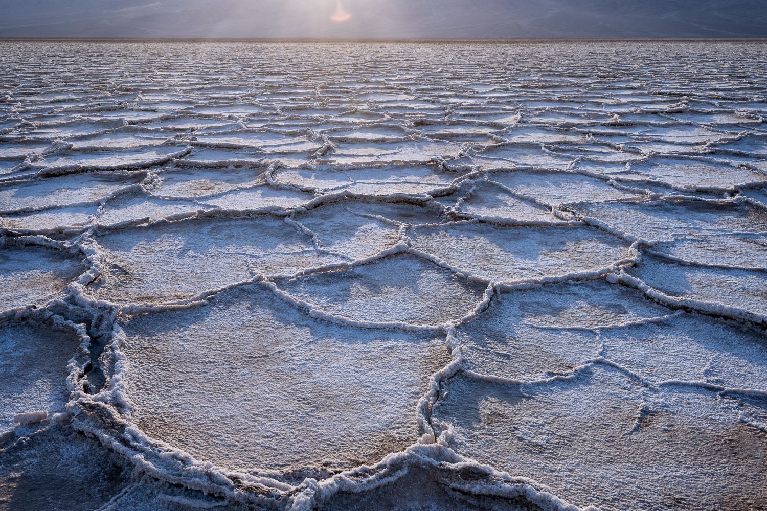Cracked salt flats patterns stretching across Badwater Basin at sunset.