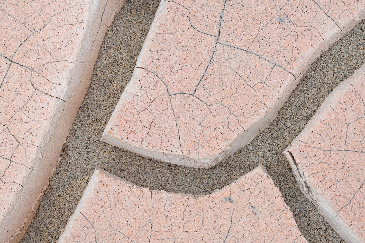 Close-up view of pink and gray cracked surface patterns resembling a river system from above.