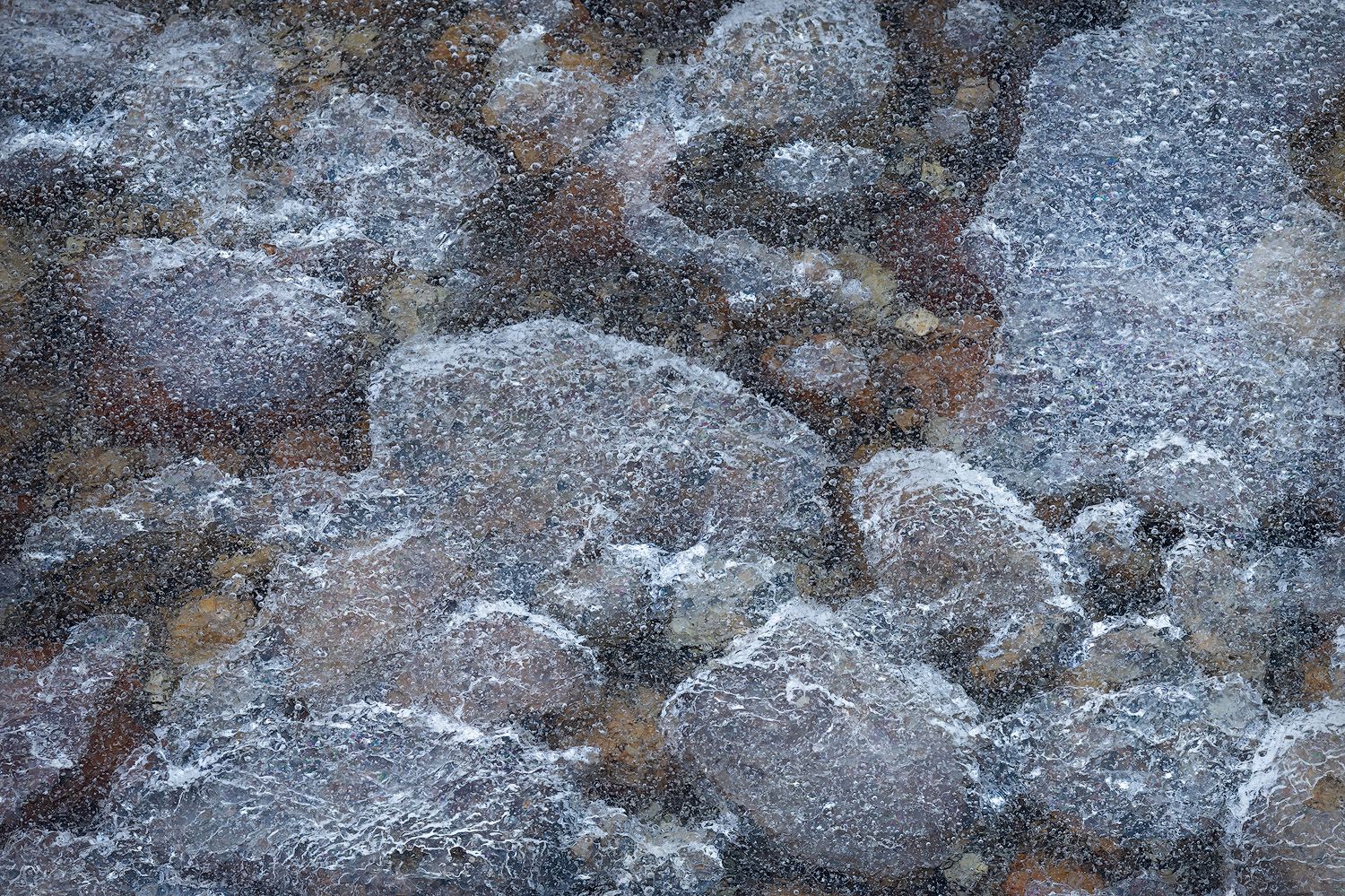 Close-up texture of frosted rocks with a crystalline pattern in grey and brown tones.