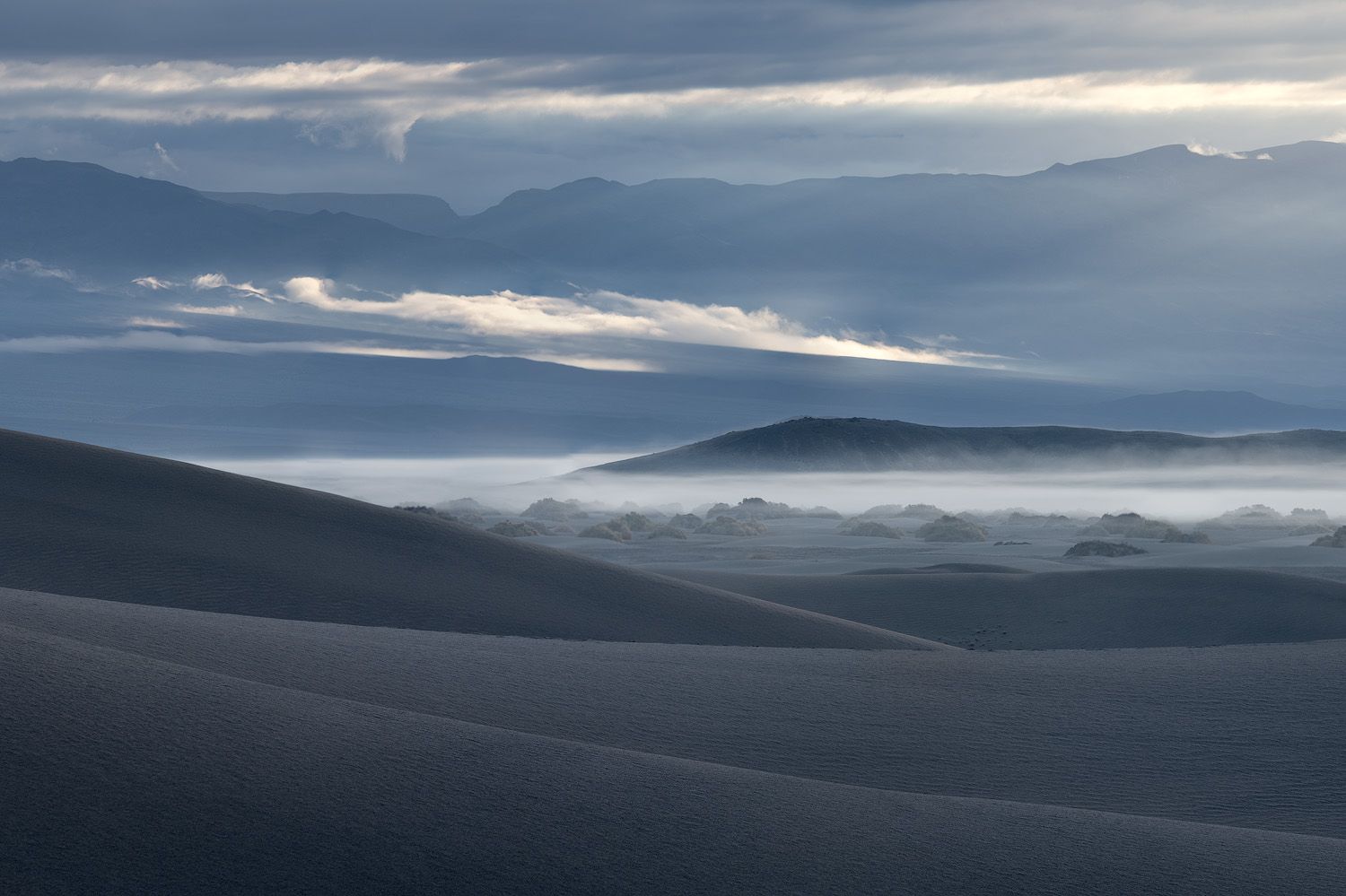 Dramatic clouds over mountain silhouettes with misty valleys in between.