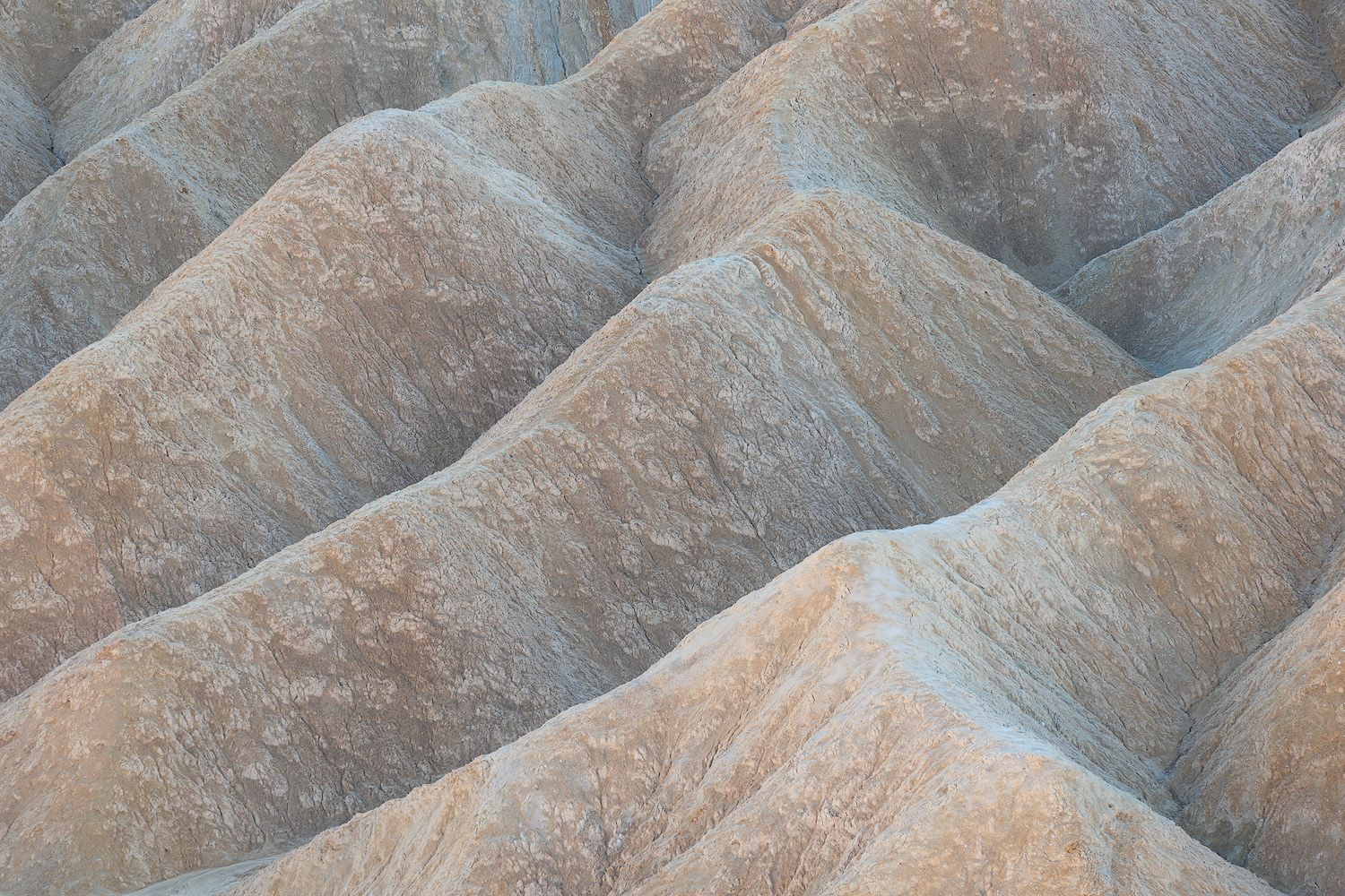 Textured rock formations with parallel ridges in warm earthy tones.