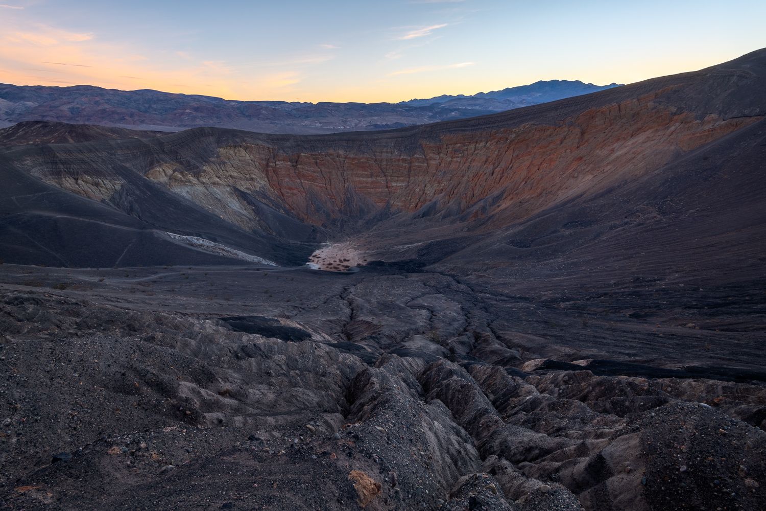 Vast crater surrounded by mountain ridges at sunrise.