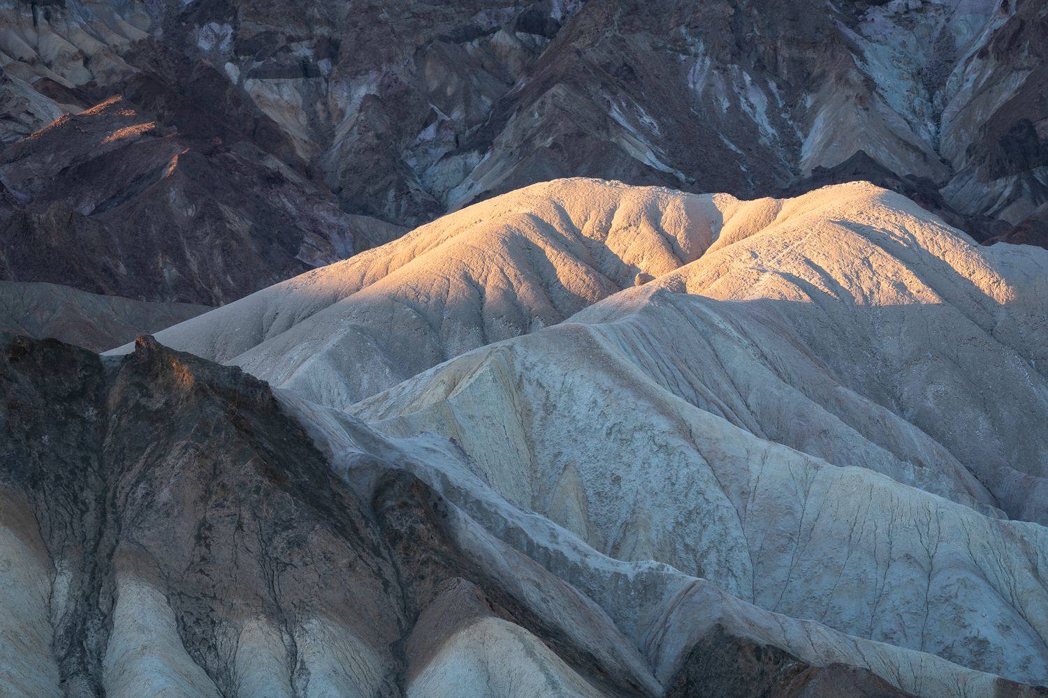 Dramatic desert landscape with deeply eroded ridges catching golden sunlight.