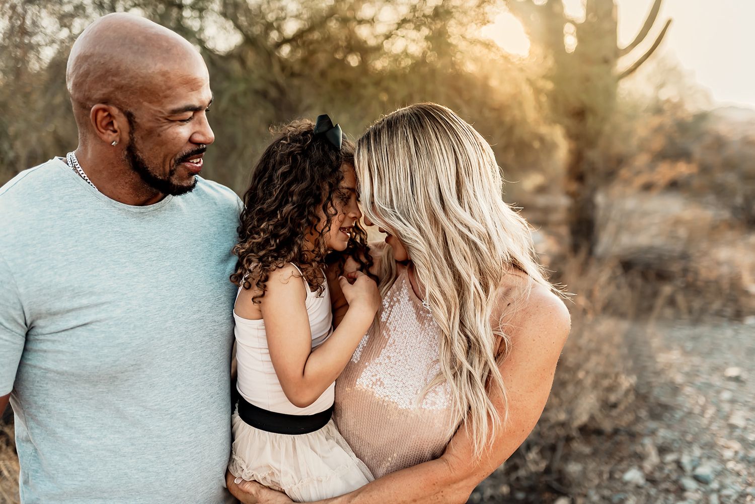 A loving family shares a tender moment together outdoors during golden hour in a natural setting.