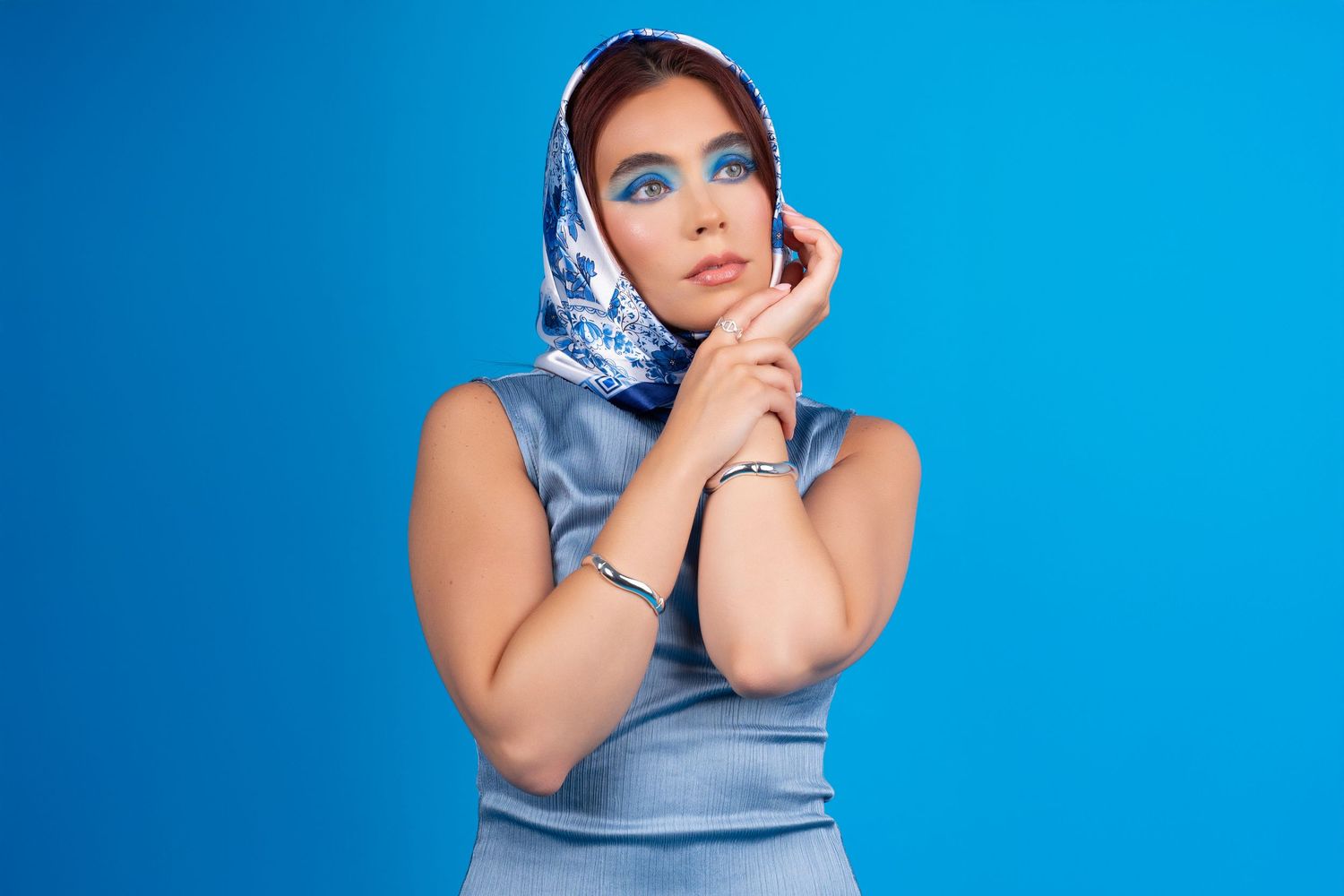 Fashion portrait of woman in blue headscarf and matching dress with bold blue eyeshadow – NYC studio shoot.
