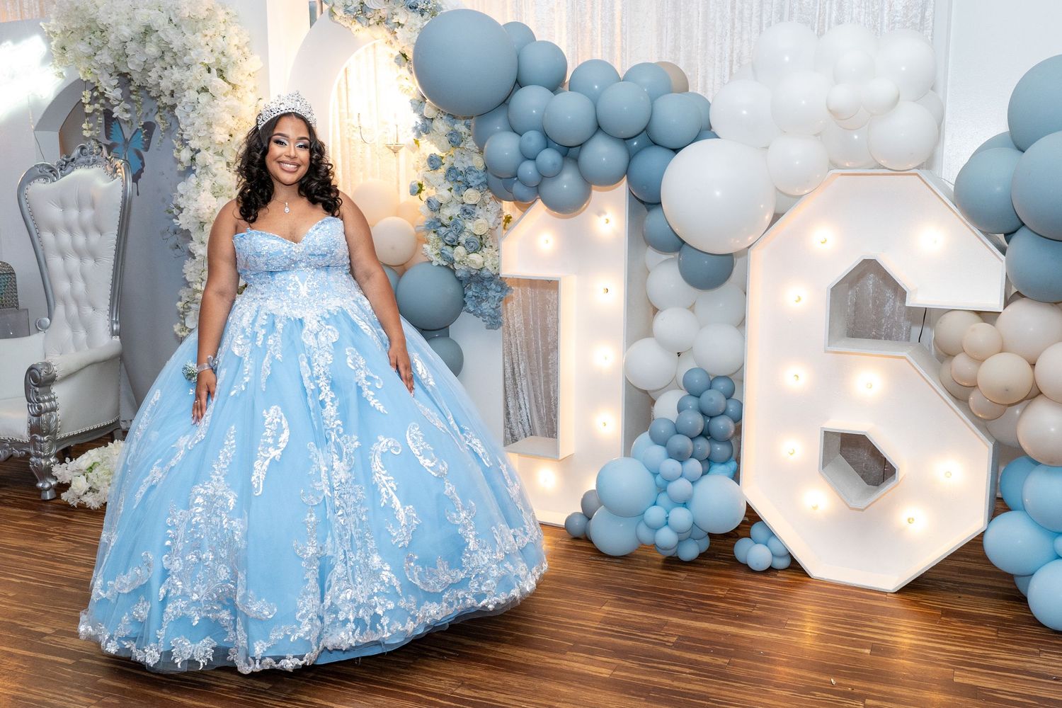 Sweet 16 portrait of girl in sparkly blue gown with large number balloons and white florals – NYC birthday session.