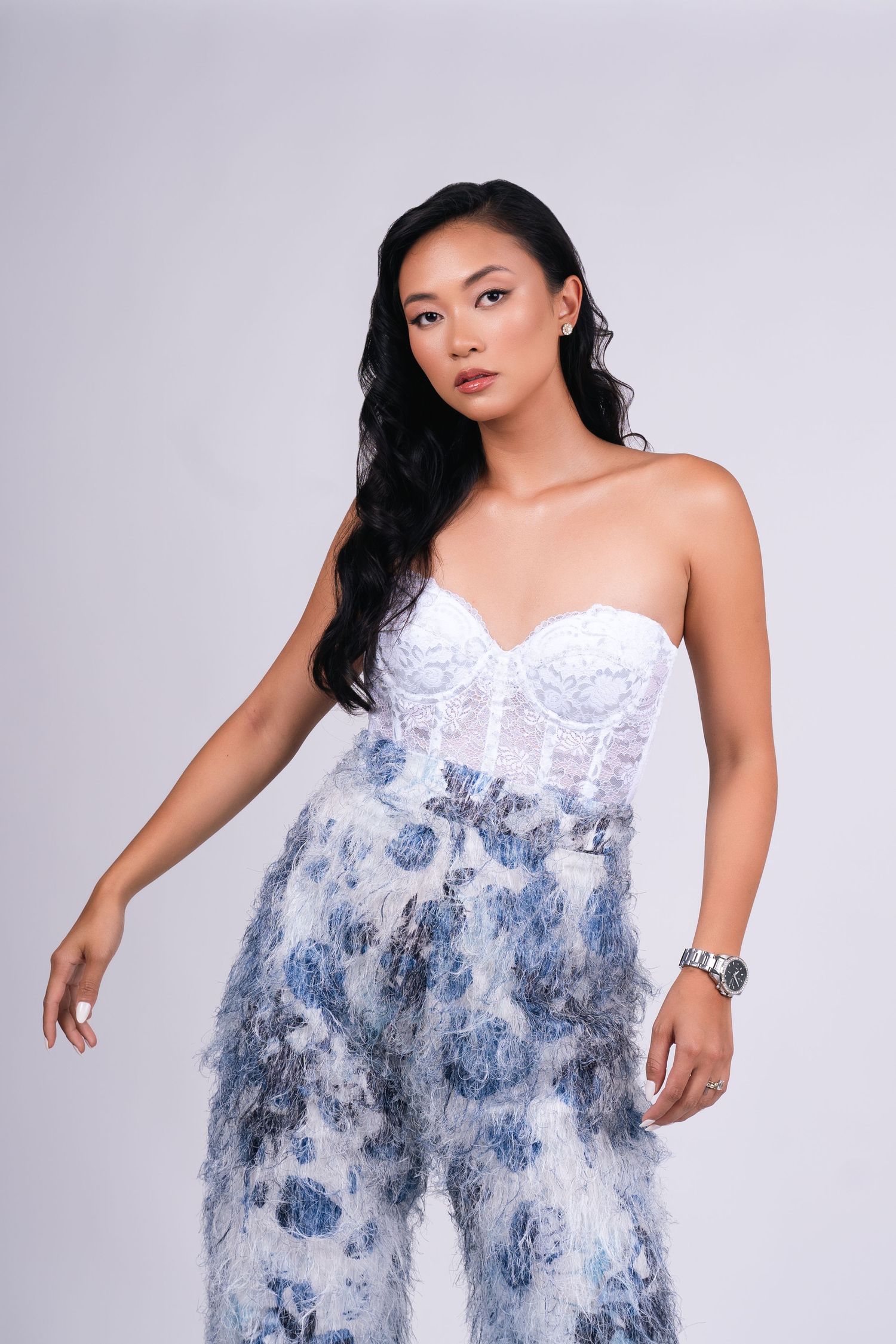 Model in white corset and textured blue pants posing confidently in minimalist NYC studio fashion shoot.