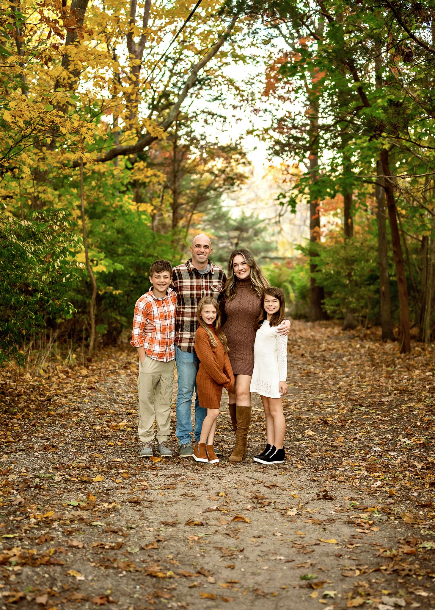 A group stands together on a leaf-covered forest path during autumn with golden trees surrounding them.