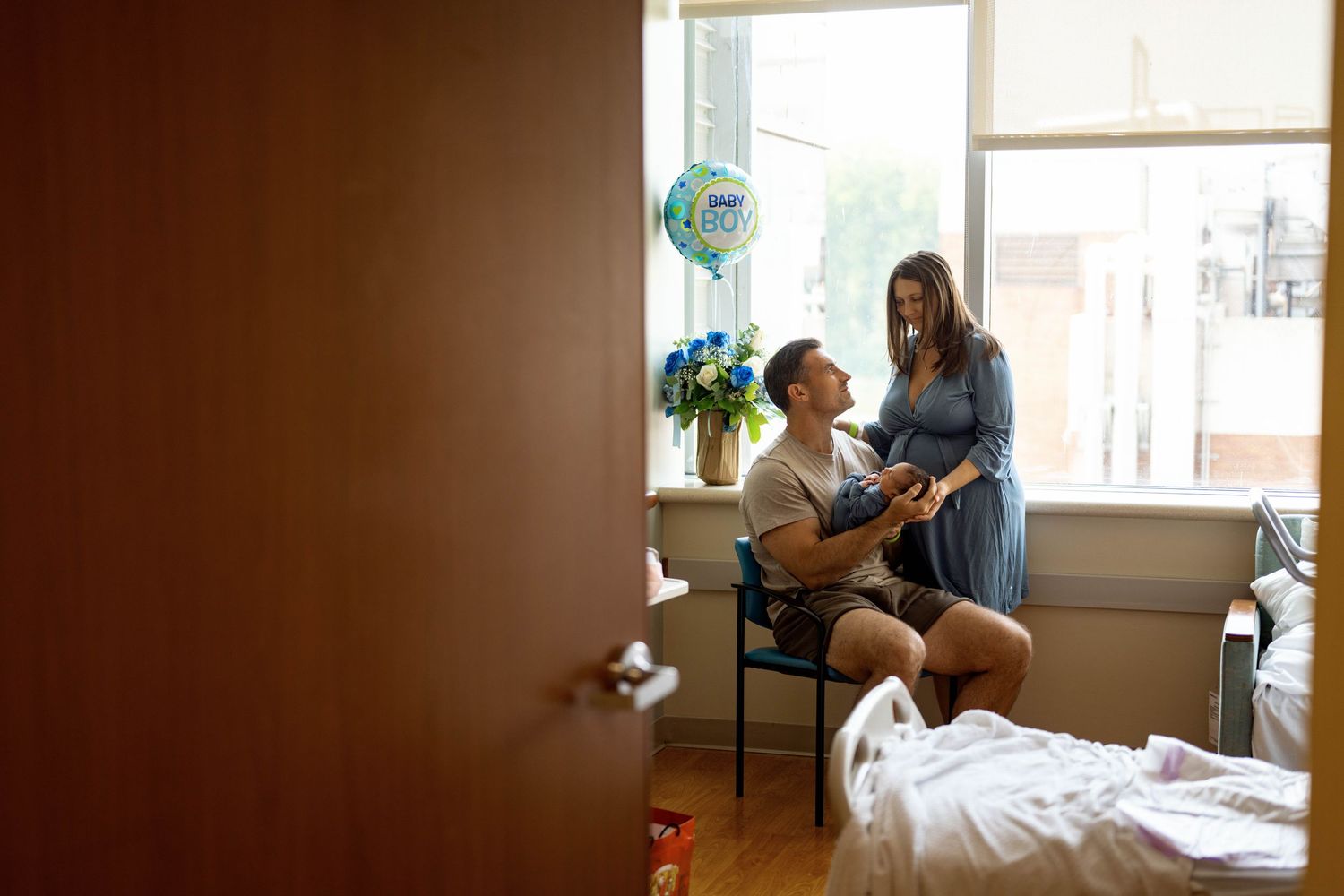 Two medical professionals discuss patient care in a bright hospital room near a window with medical equipment visible.
