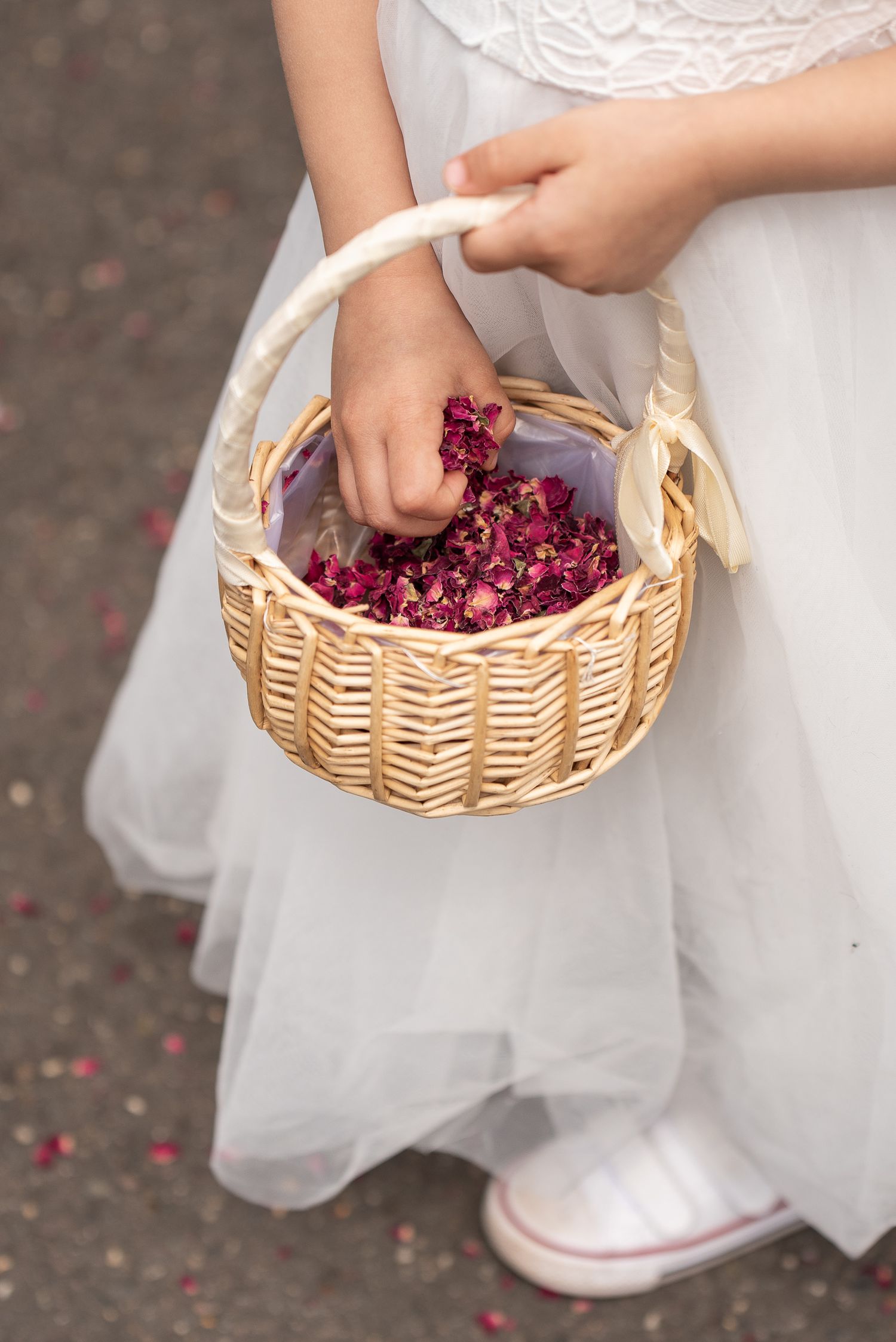 Bridesmaid holds a basket of pink petal confetti and is reaching her hand in